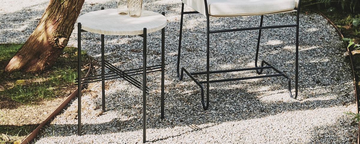TS Outdoor Side Table and Tropique Dining Chair in an outdoor courtyard setting