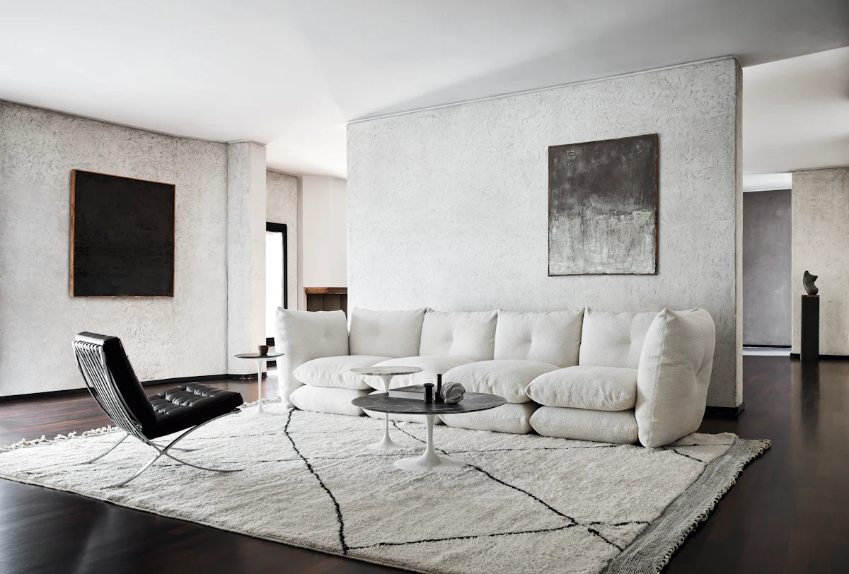 Living room with white sofa set and large rug, artwork on walls, modern decor