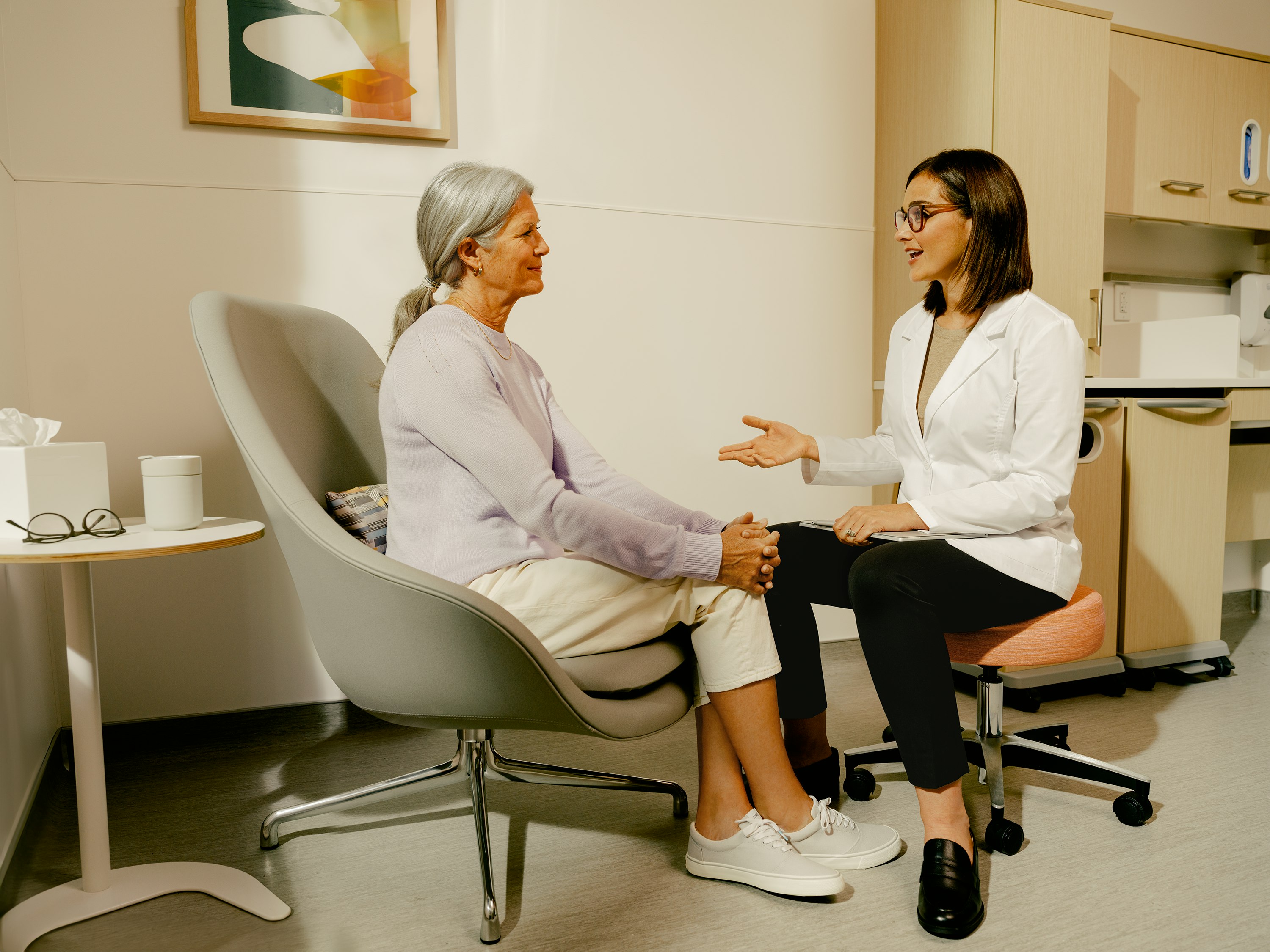 Female patient in an exam room with a female physician having a conversation.