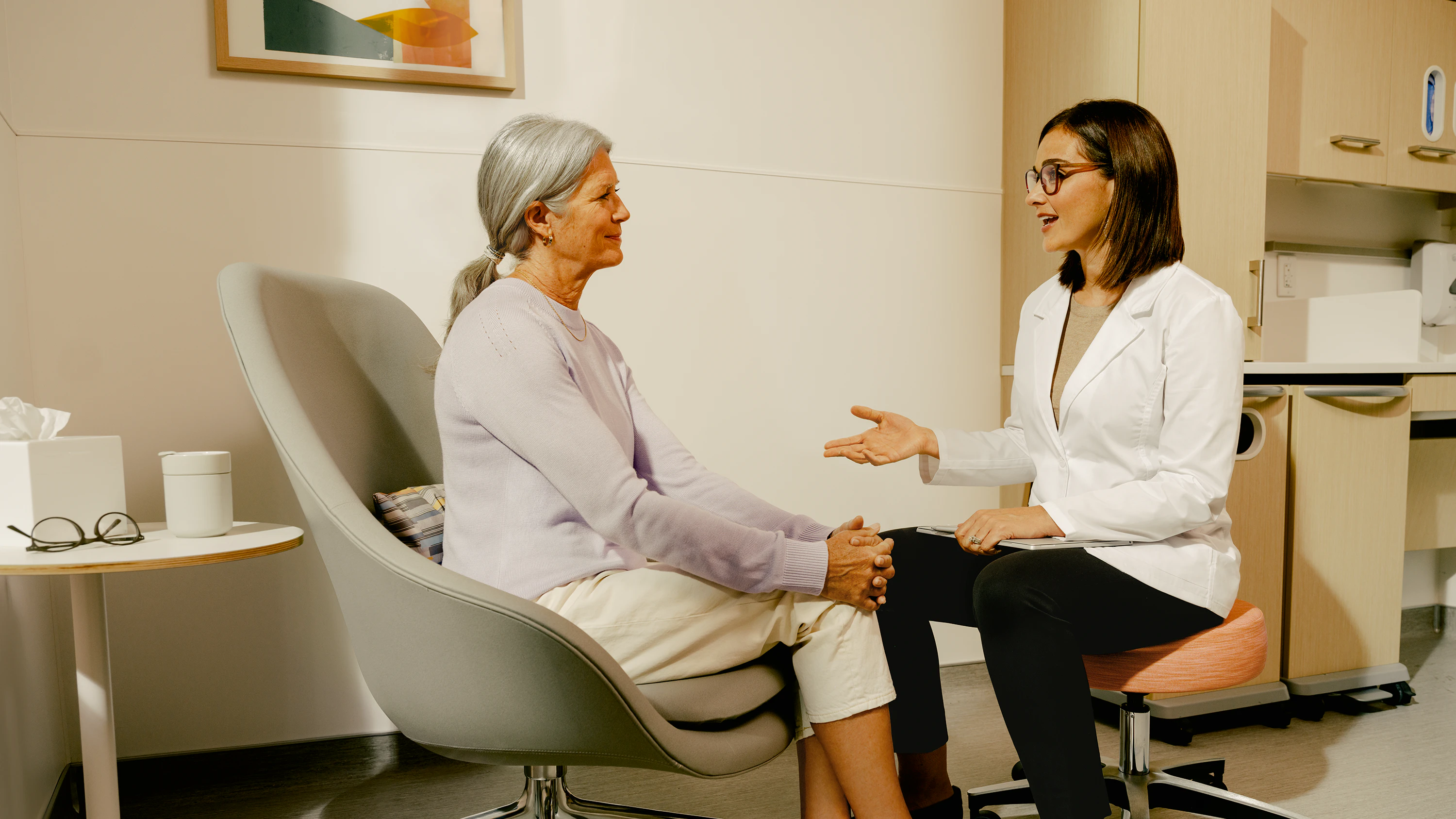 Female patient in an exam room with a female physician having a conversation.