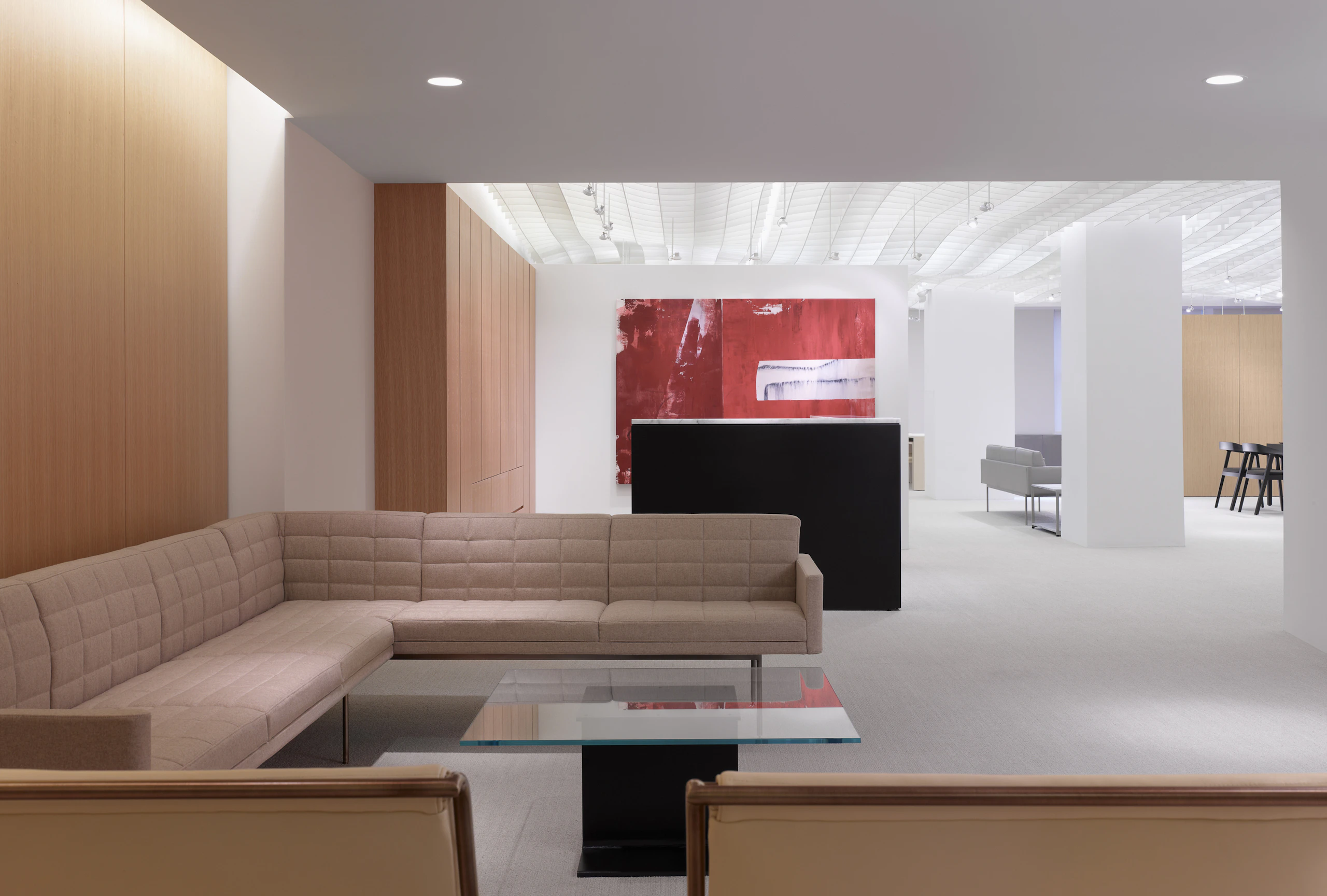 A lobby lounge featuring a beige Tuxedo Component sectional and a square I Beam coffee table with a black pedestal and glass top.
