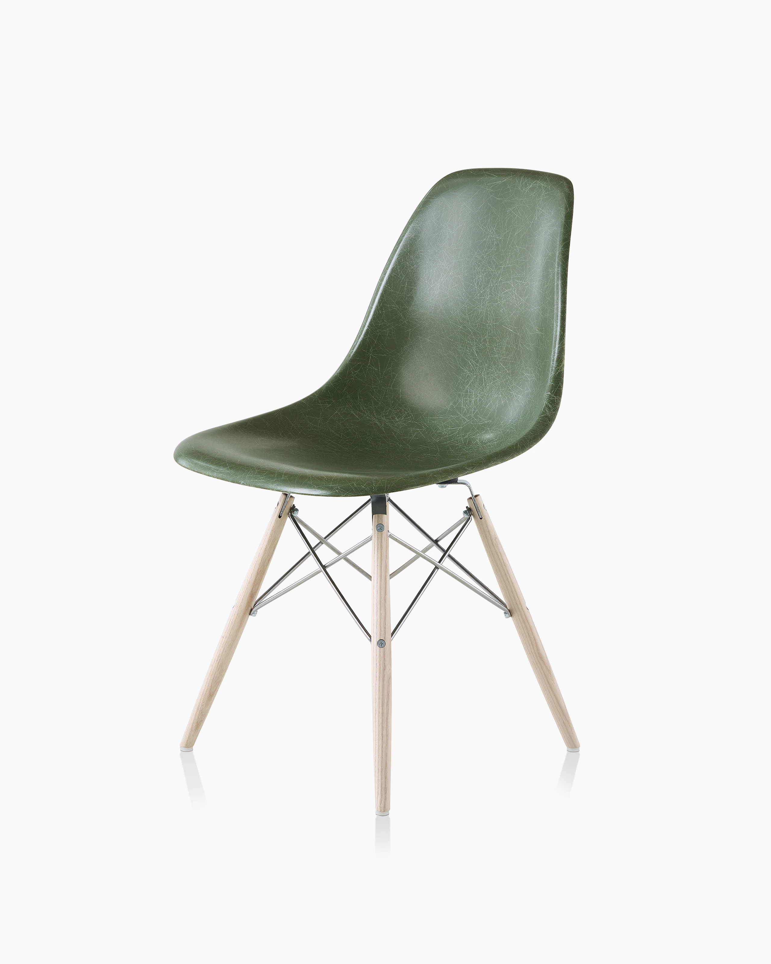An Eames Molded Fiberglass Side Chair with a dowel base and dark green seat, viewed at an angle.
