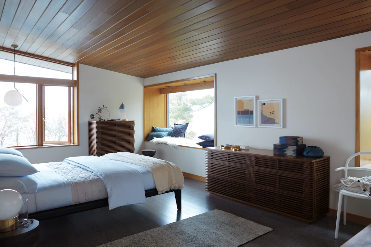 Bedroom scene with two wooden slatted dressers, bed nearby