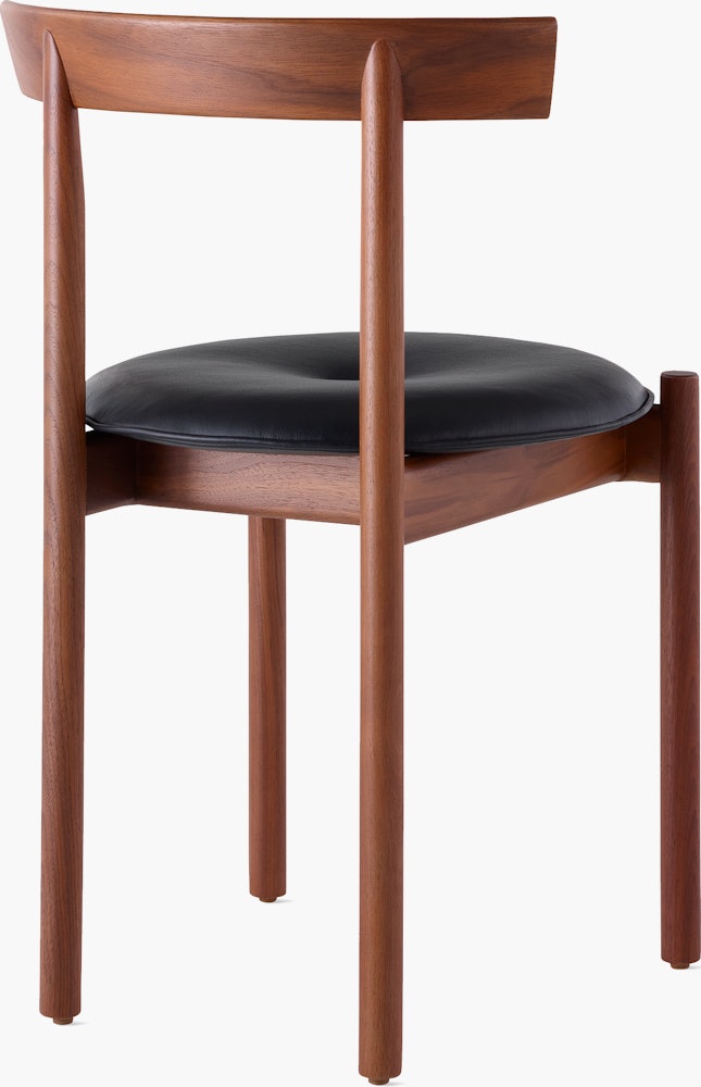 A walnut Comma Chair with a seat pad, viewed from the back at an angle.