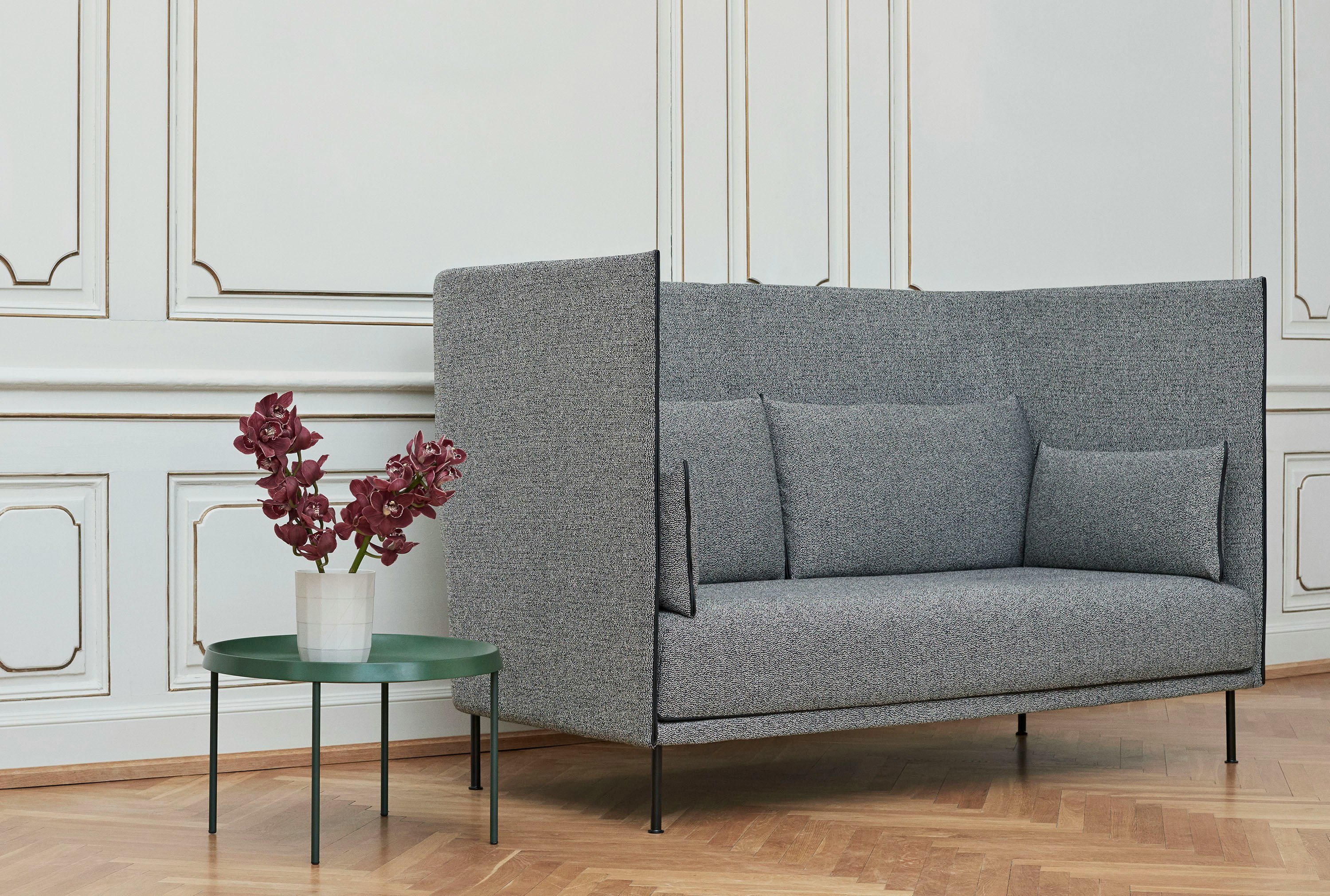 A grey high back Silhouette Sofa next to a Tulou table.