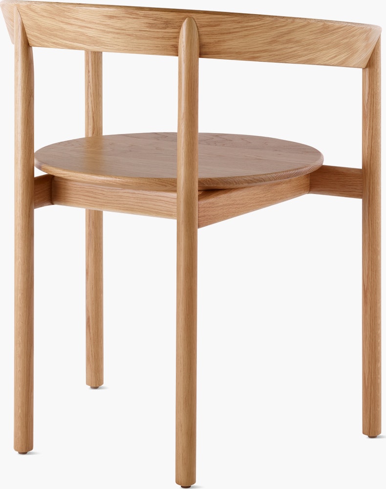 An oak Comma Chair with arms, viewed from the back at an angle.