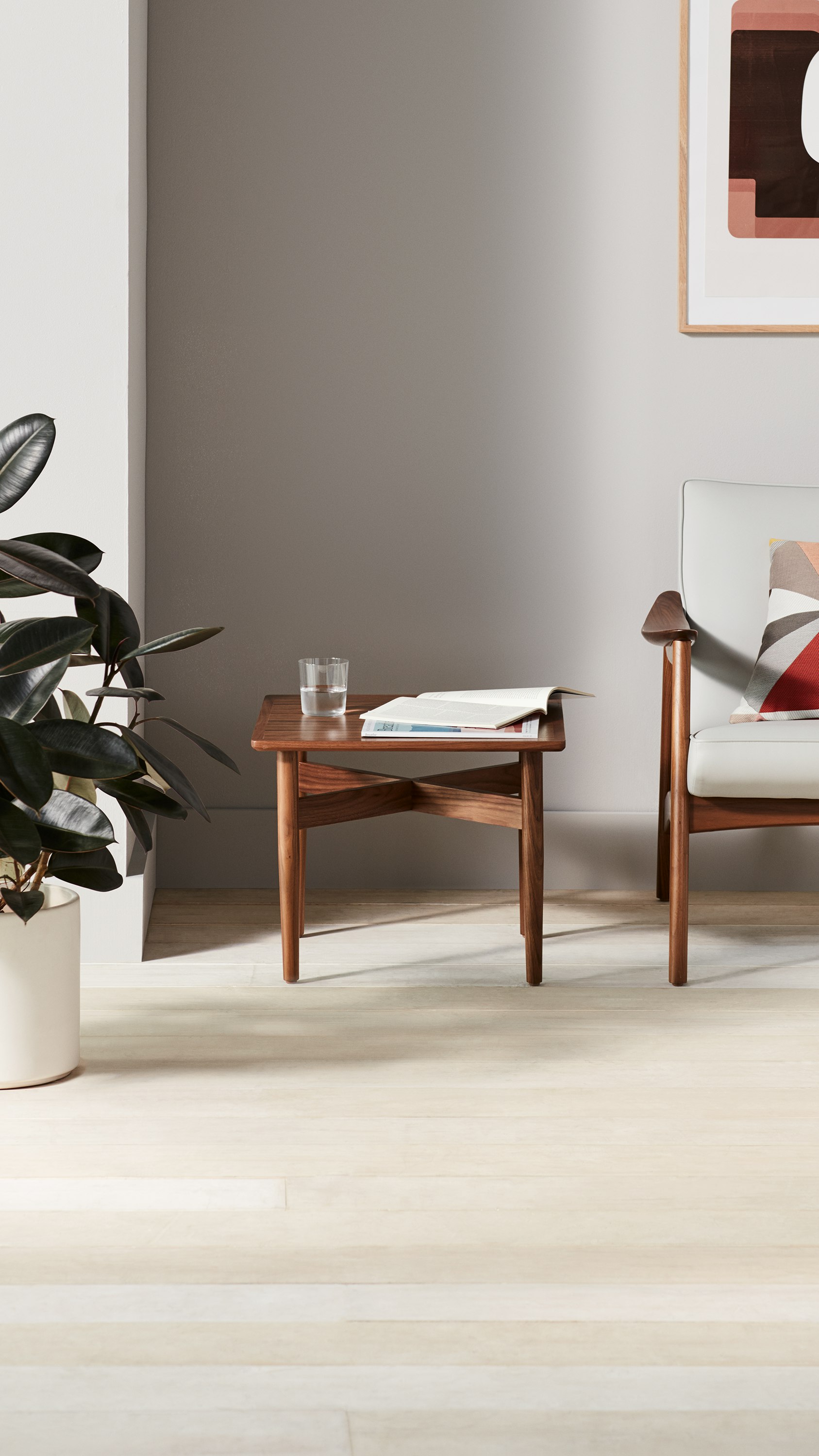 Waiting room with a walnut wood square Hemlock Side Table and a lounge chair upholstered in light gray and a walnut base.