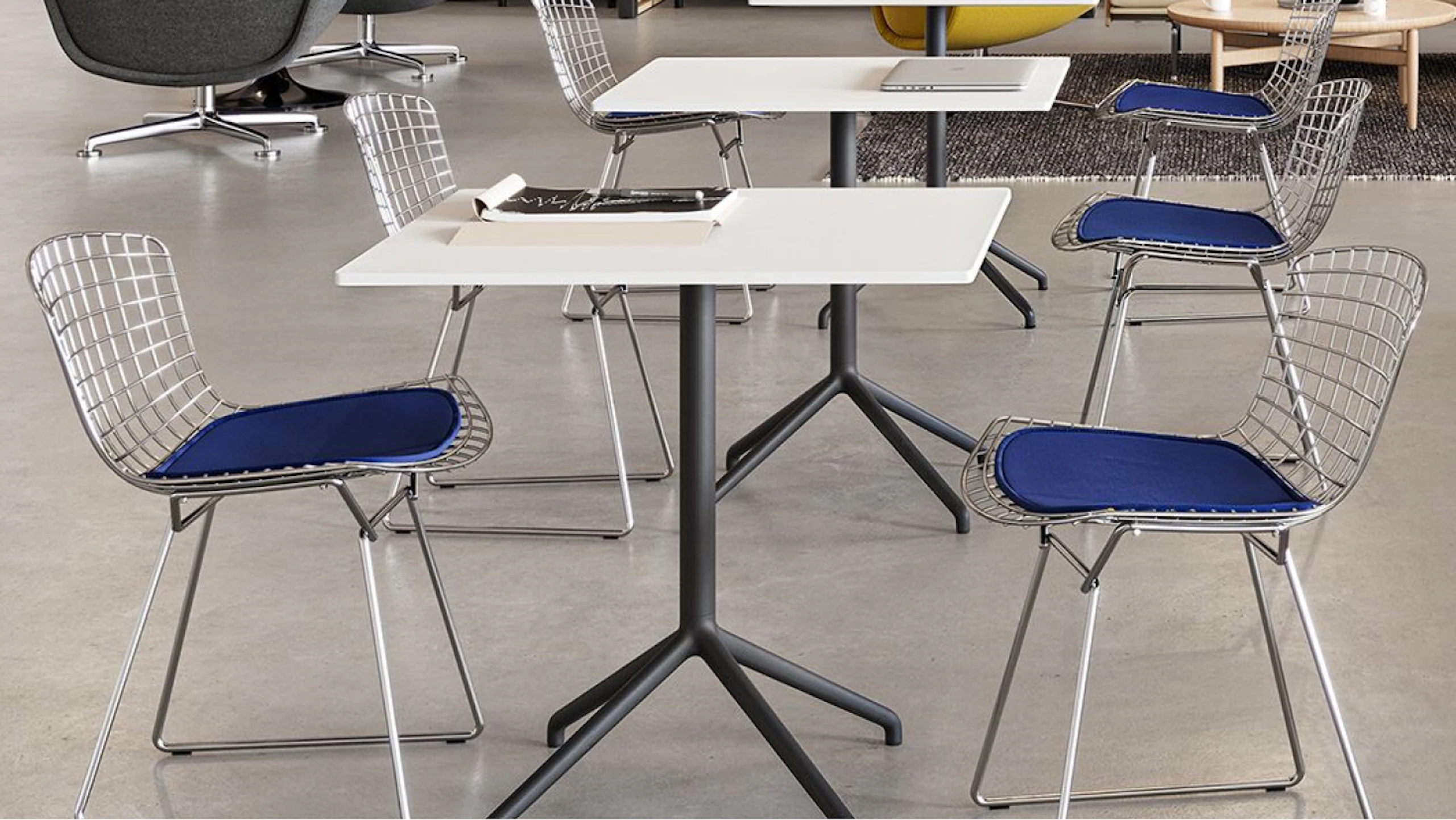 Two black and white Muuto Still Cafe tables feauting Knoll Bertoia chairs used to facilitate flexibility in a café setting