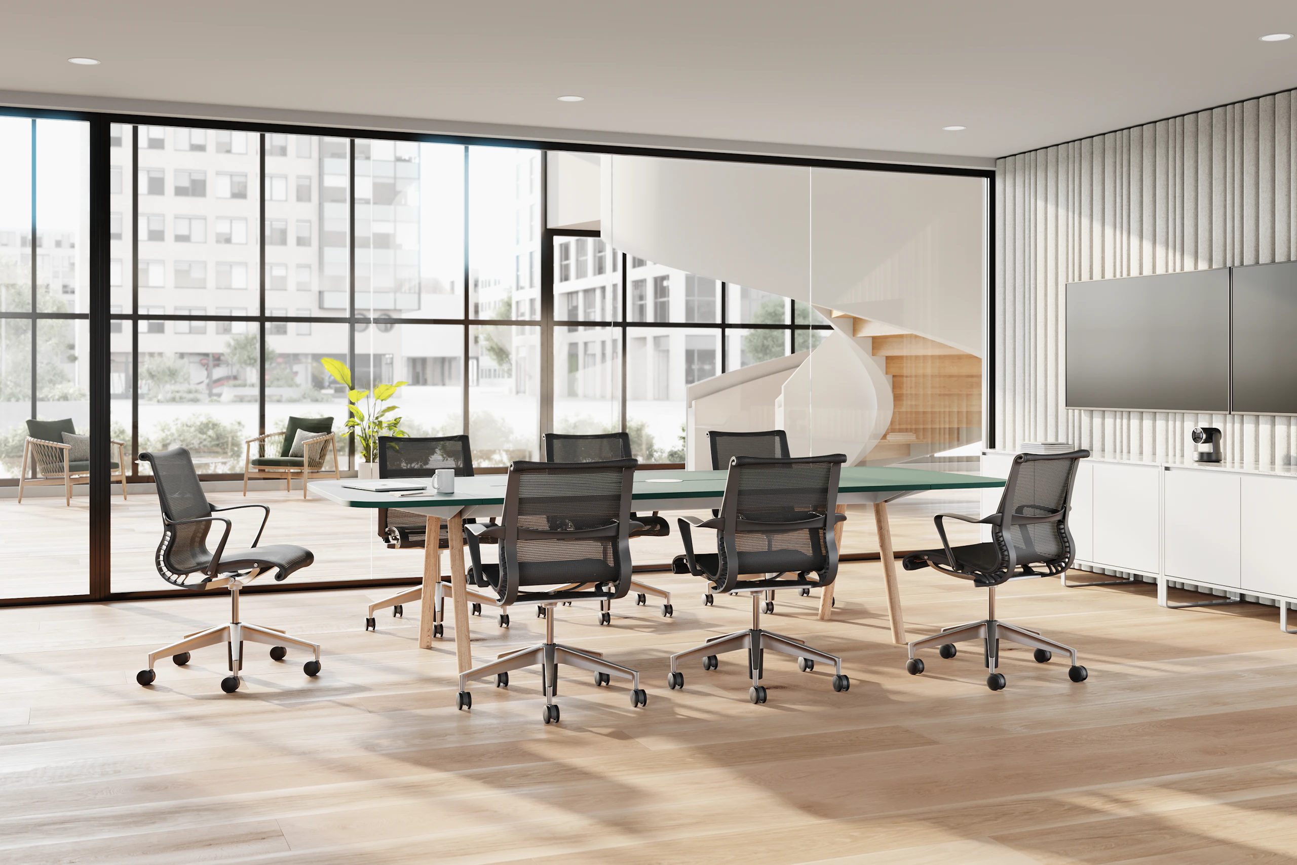 Seven Setu chairs in dark grey surround a table in a conference room with a monitor.