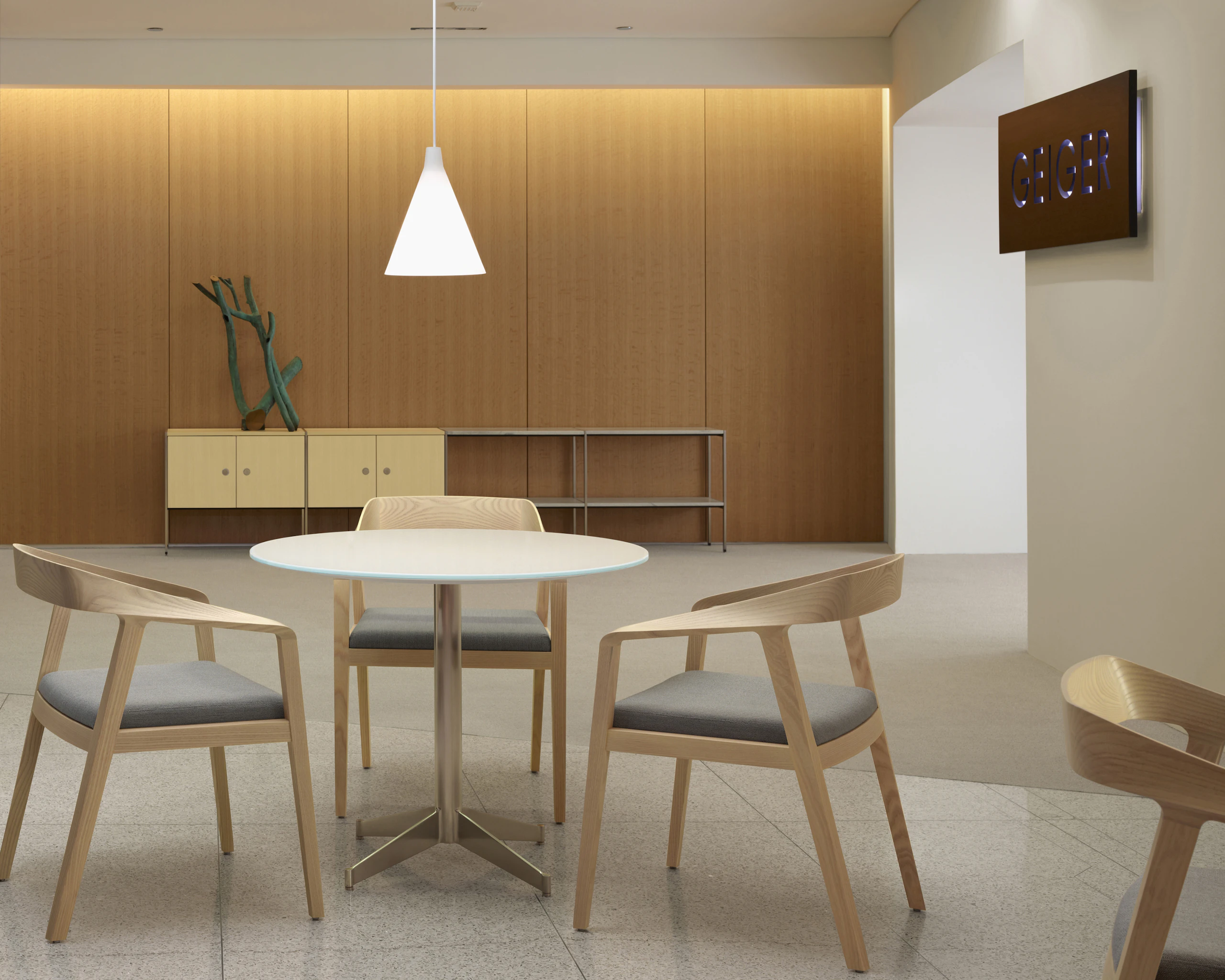 An interaction space with three Full Twist Guest Chairs around a table in the foreground and an H Frame Storage credenza against the back wall.