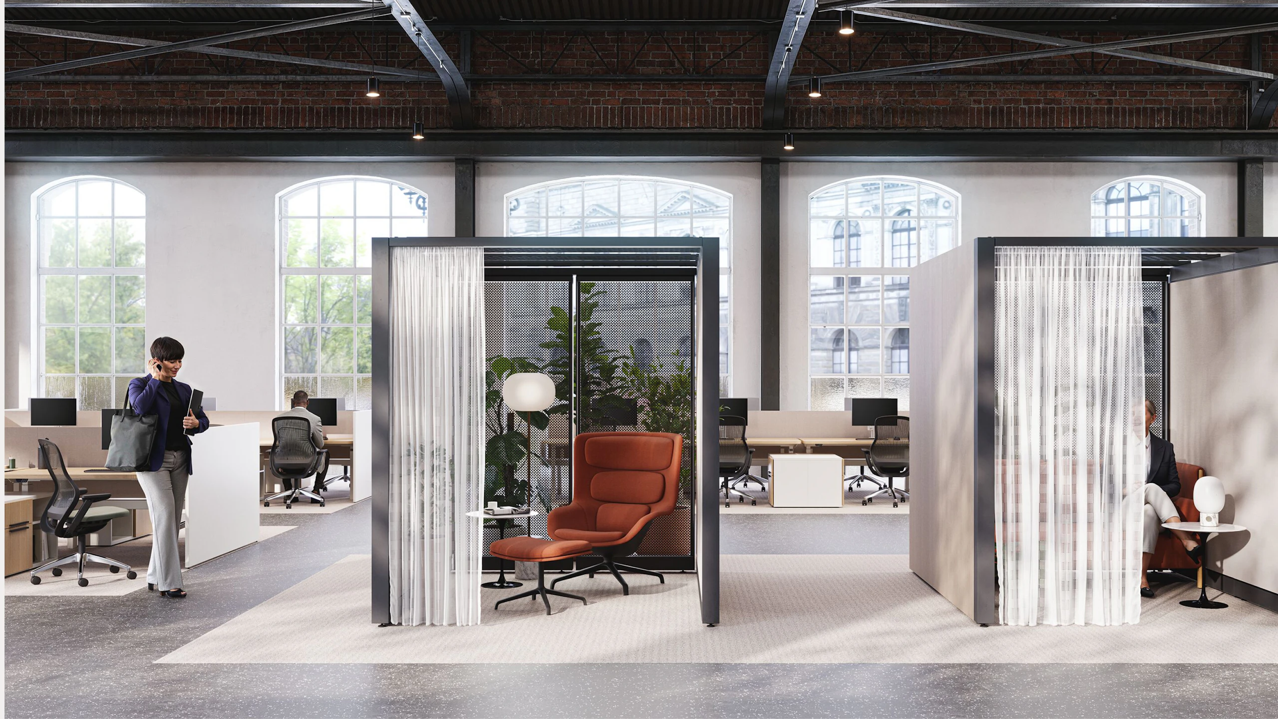An open, brightly lit space with brick walls and floor-to-ceiling windows featuring Knoll Rockwell Unscripted Creative Walls, Saarinen Side Tables, burnt-orange lounge chairs, and lighting from Design Within Reach