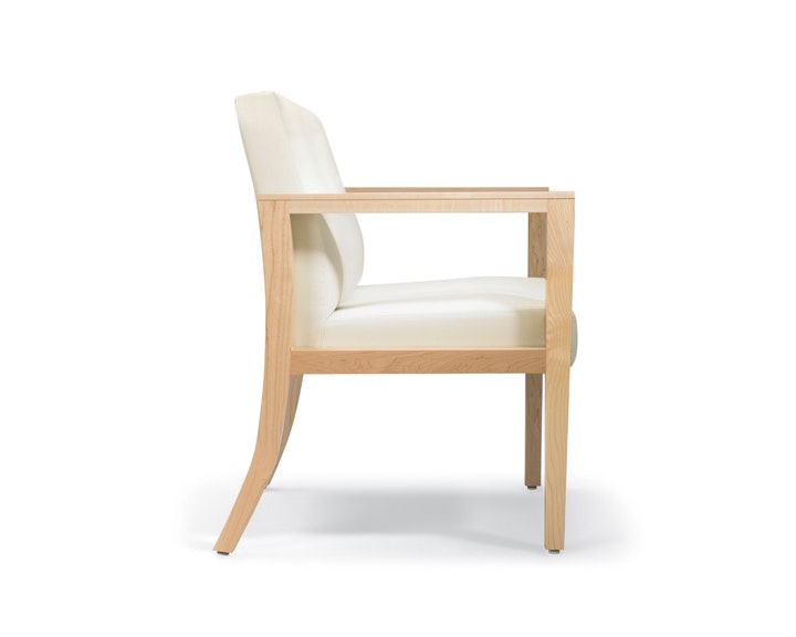 A side view of Brava 863 plus chair in white textile with open maple wood arms.