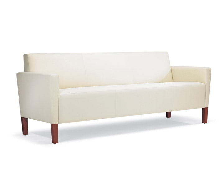 A three-quarter view of a Brava Classic Lounge Sofa with white textile and upholstered arm caps.