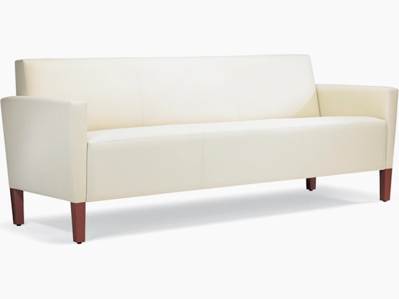 A three-quarter view of a Brava Classic Lounge Sofa with white textile and upholstered arm caps.