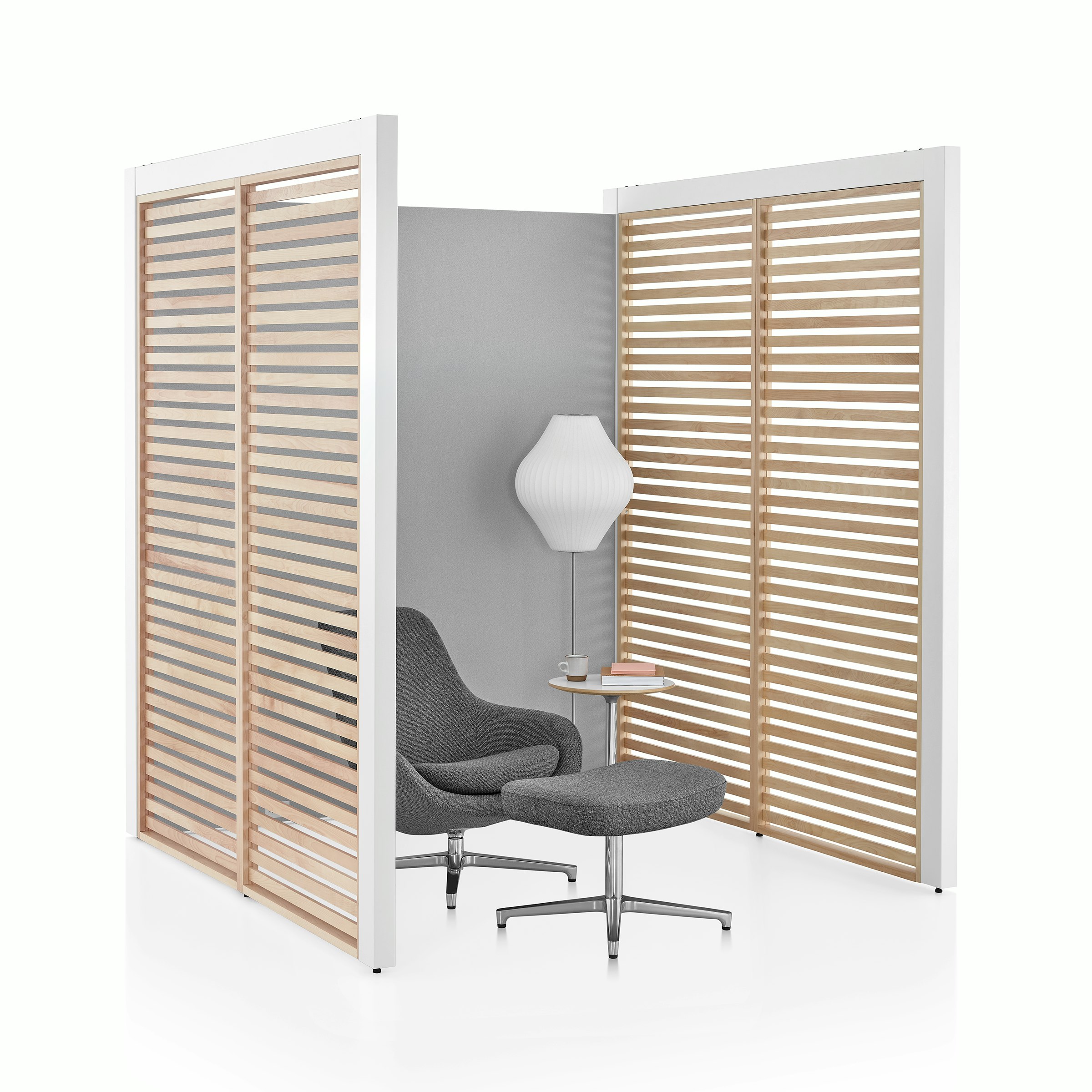 A three-sided Overlay space with birch wood slat side walls and gray fabric back wall with a lounge chair and side table inside.