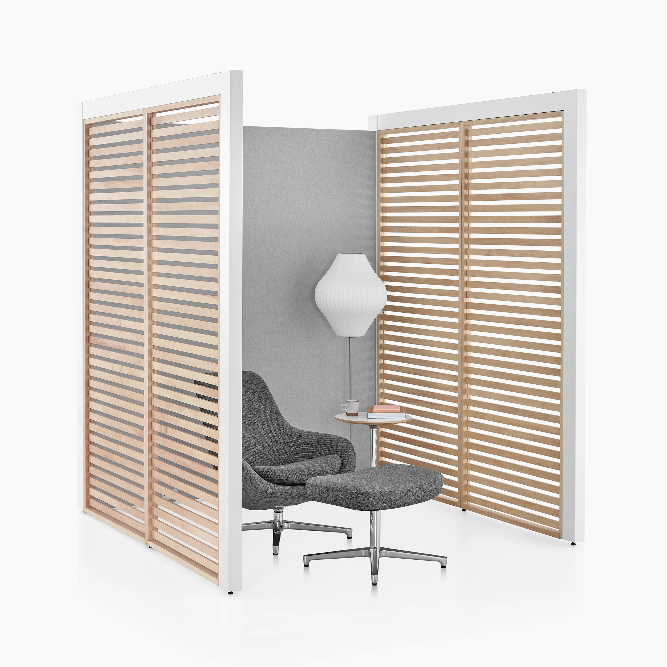 A three-sided Overlay space with birch wood slat side walls and gray fabric back wall with a lounge chair and side table inside.