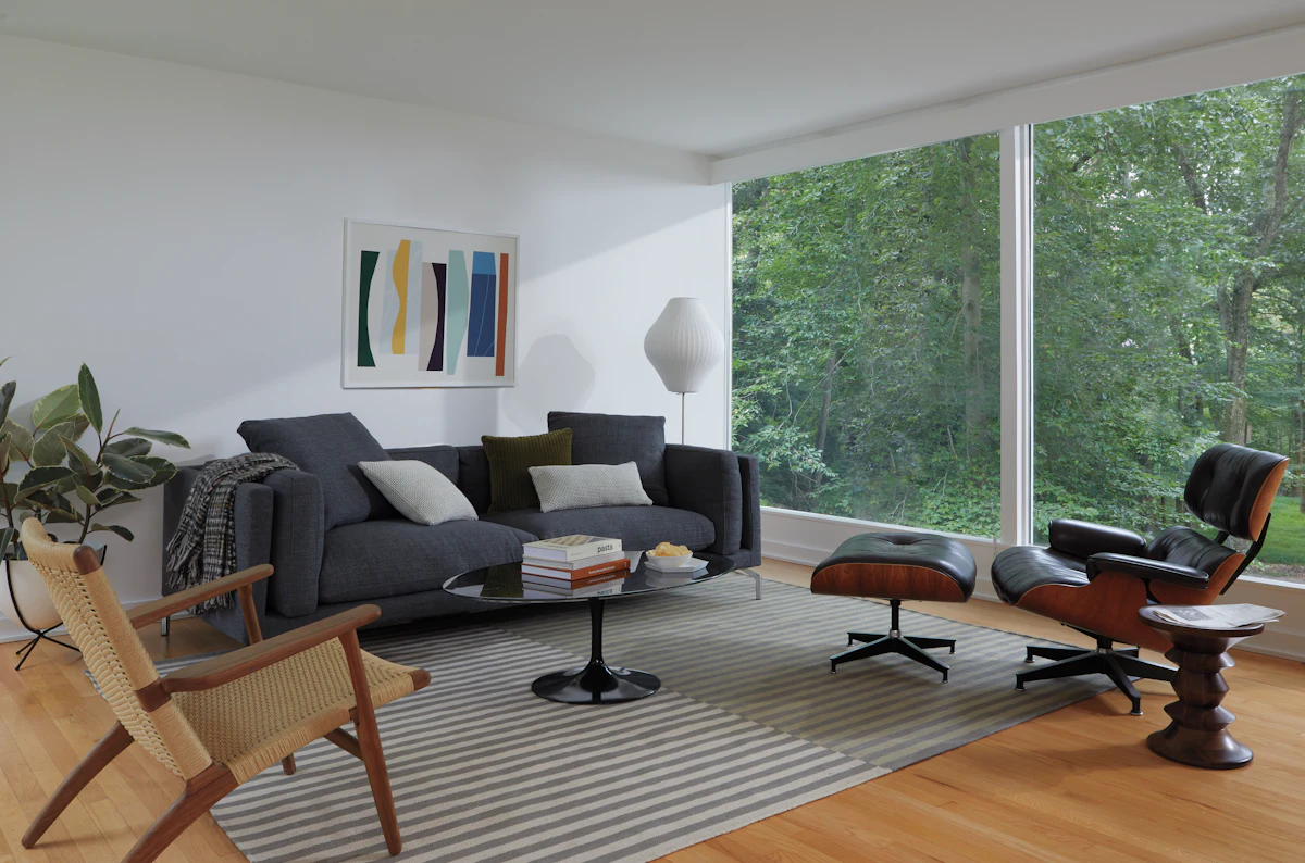Living room with dark gray sofa and big windows overlooking greenery