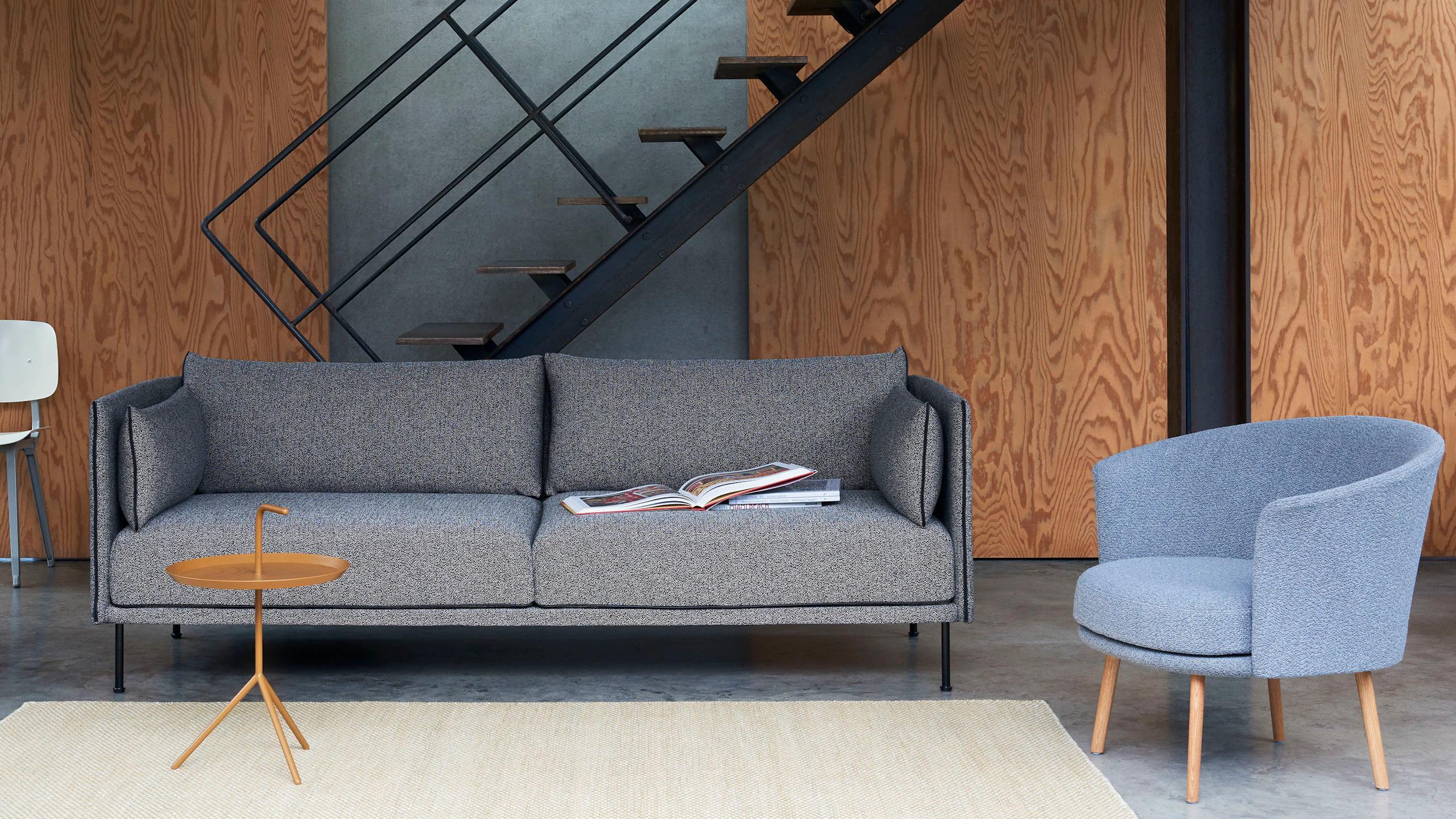 A grey Silhouette Sofa with a orange Don't Leave Me Side Table and blue Dorso chair.
