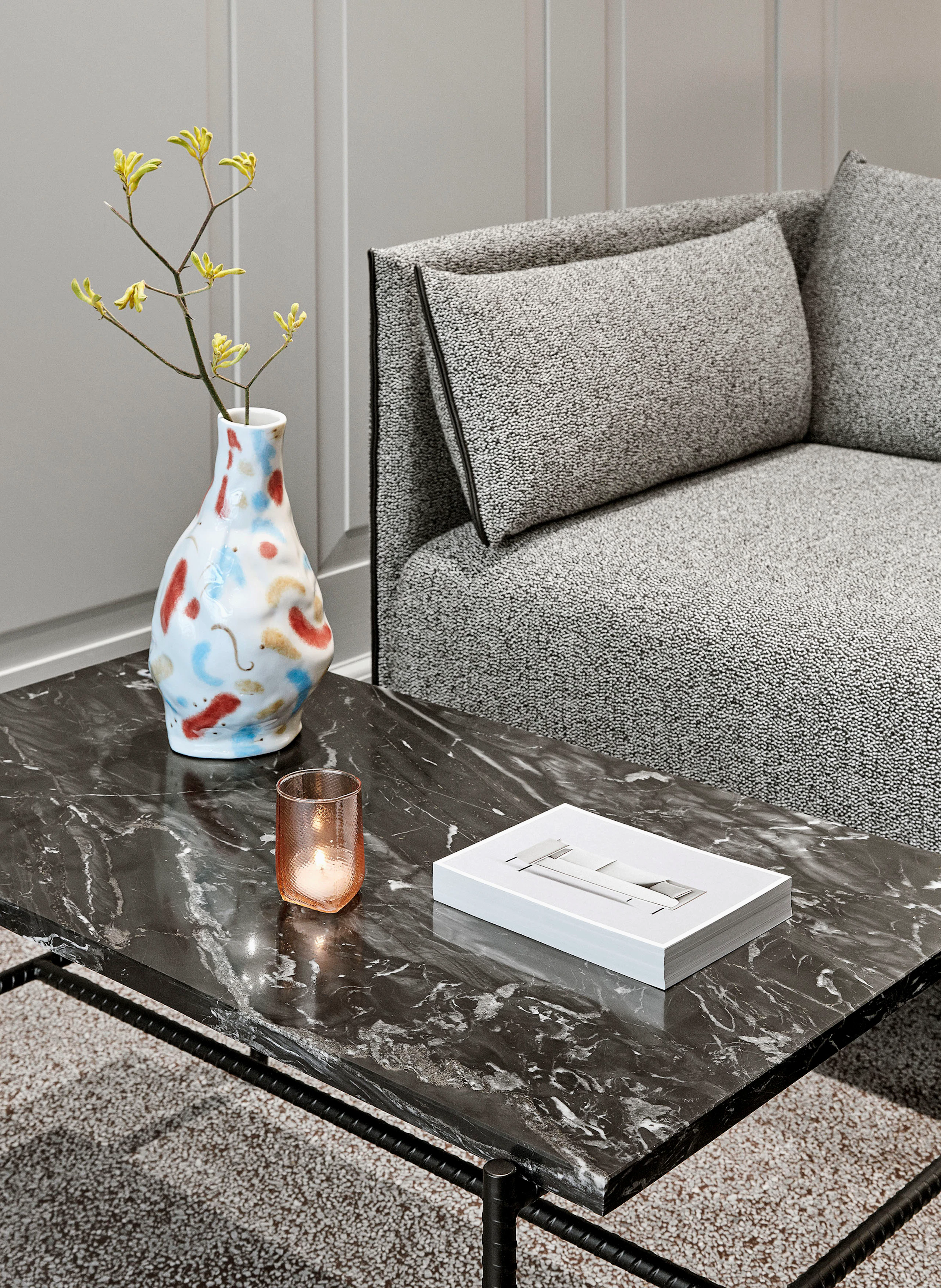 A Rebar Coffee Table with a marble top next to a grey sofa.