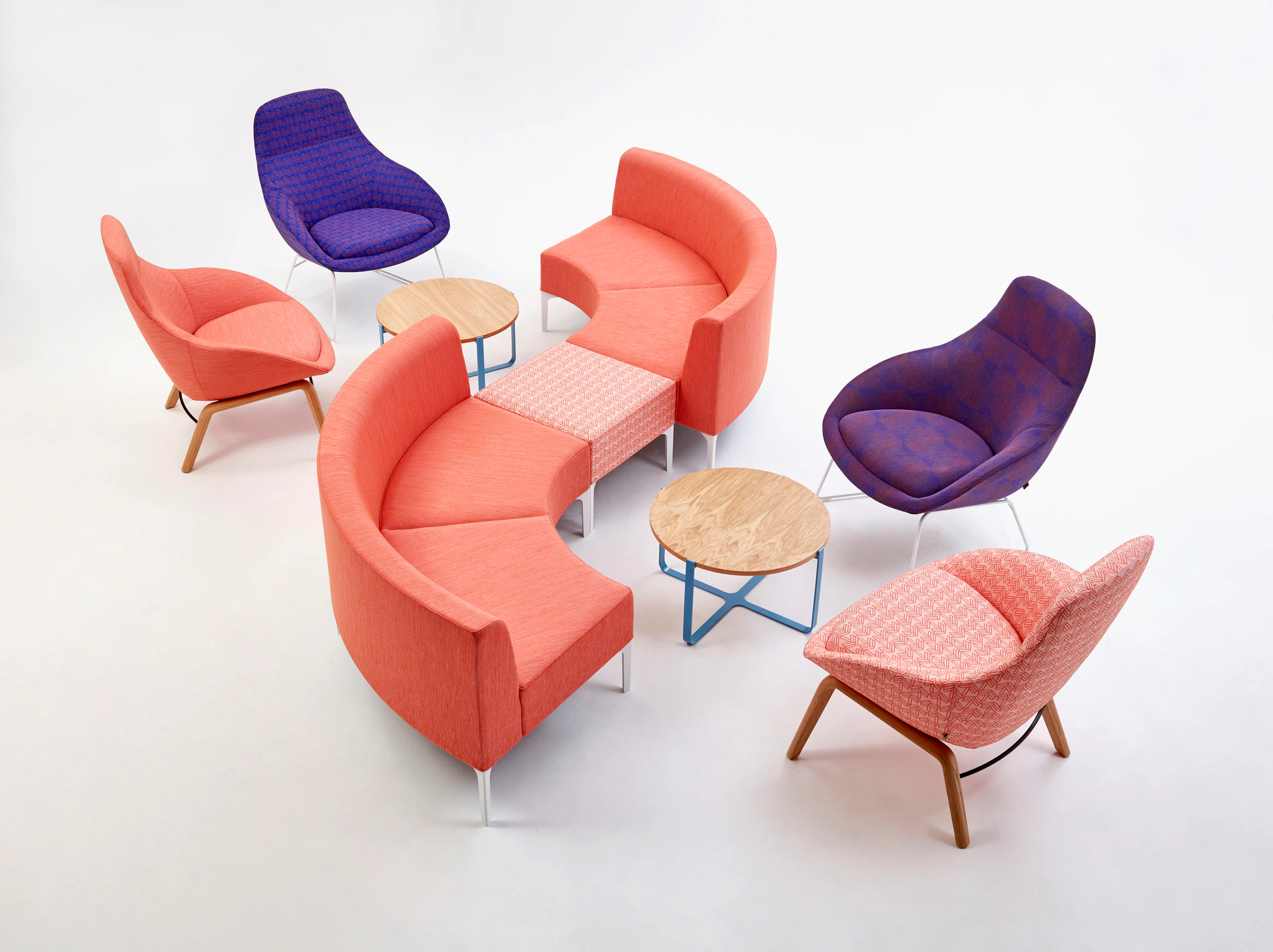 An orange patterned single Symbol Bench joining two orange 90 degree Symbol Modular Seating pieces with four Always Lounge Chairs.