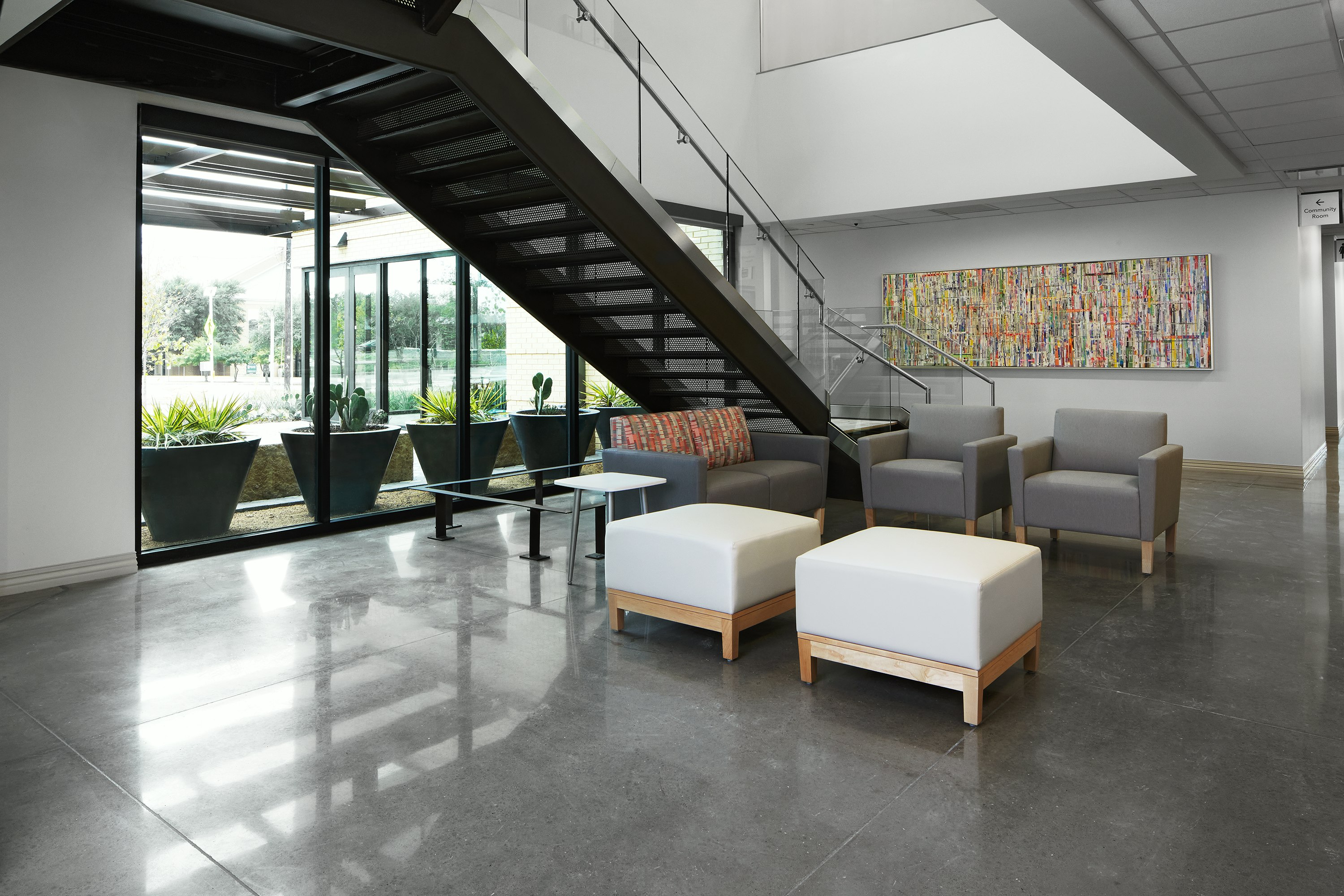 Lobby waiting area with Nemschoff Brava Classic Armchair in gray and Nemschoff Brava Classic Multiple Seating in a gray seat and multicolored back with Nemschoff Brava Platform Bench in soft white seat and wood base with a Nemschoff Palisade Side Table in a white top and silver base.