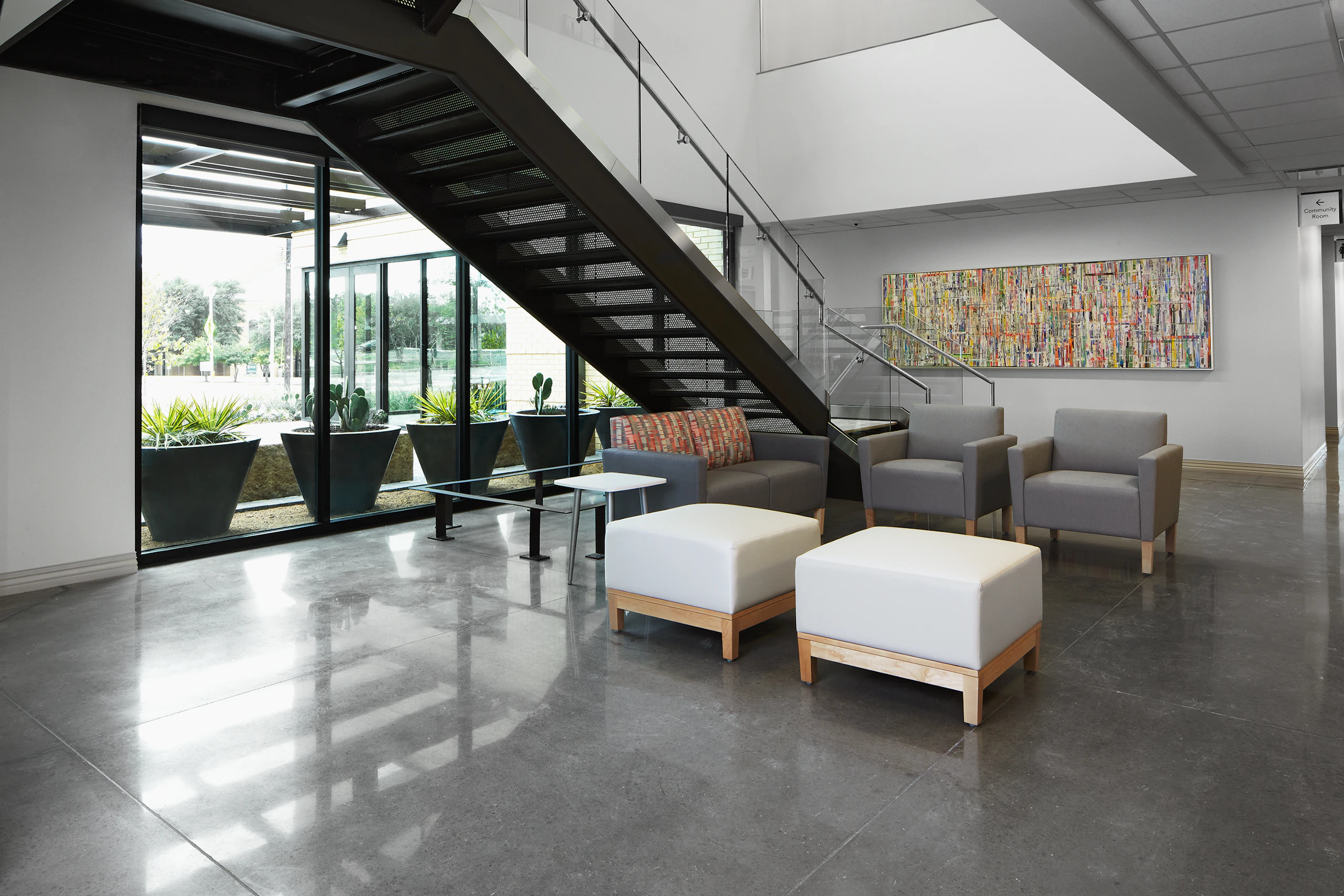 Lobby waiting area with Nemschoff Brava Classic Armchair in gray and Nemschoff Brava Classic Multiple Seating in a gray seat and multicolored back with Nemschoff Brava Platform Bench in soft white seat and wood base with a Nemschoff Palisade Side Table in a white top and silver base.