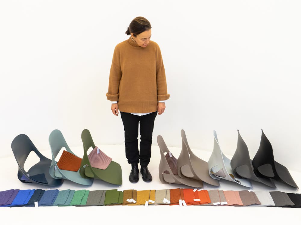 Carola Zwick from Studio 7.5 standing and looking at the shell and material colors available for the Zeph chair.