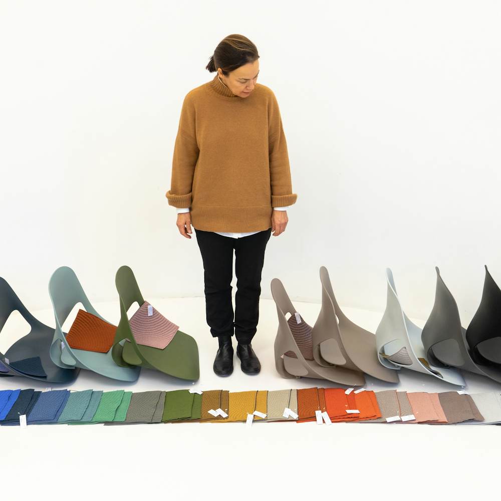 Carola Zwick from Studio 7.5 standing and looking at the shell and material colors available for the Zeph chair.