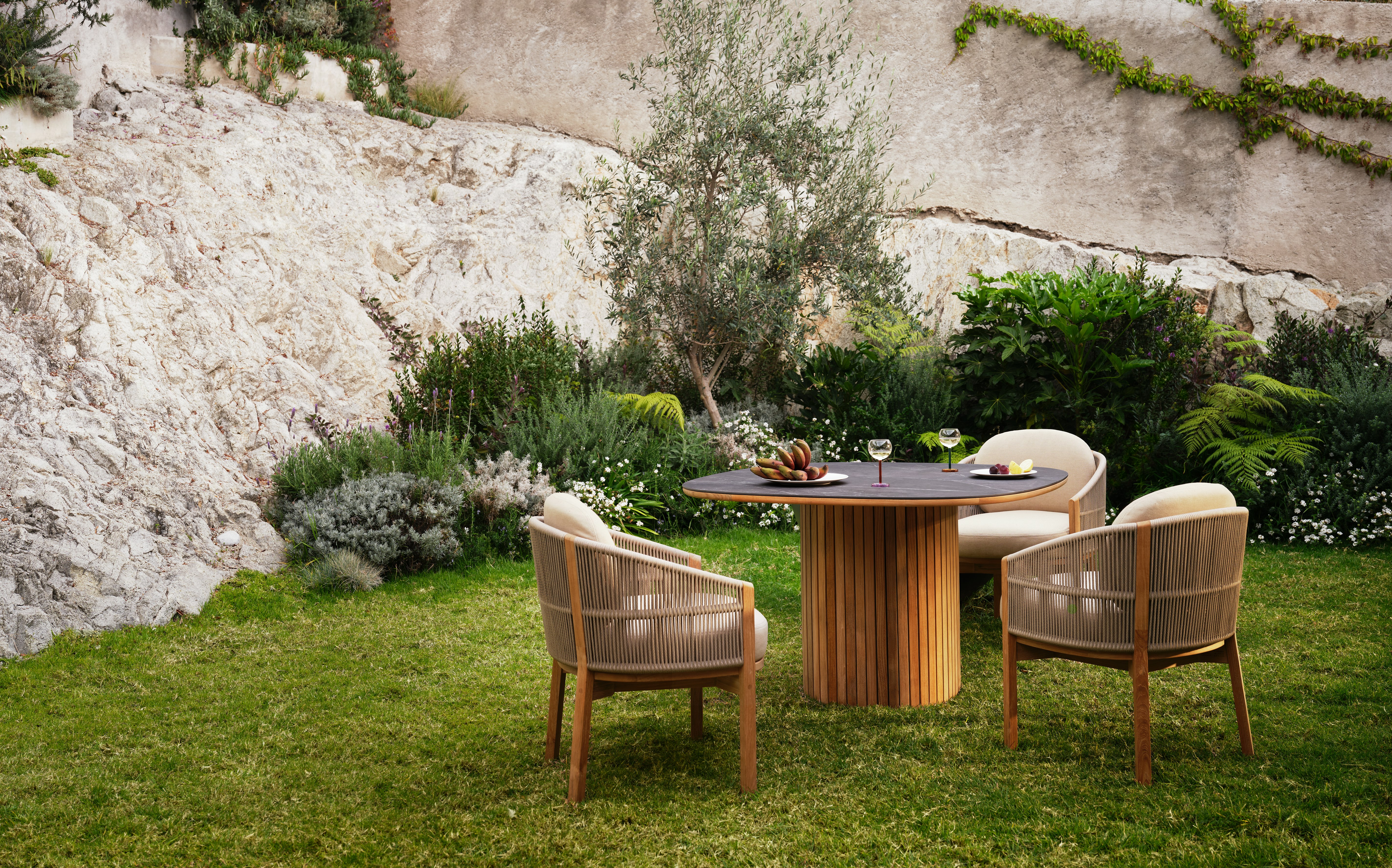 Softlands Outdoor Dining Table surrounded by three Softlands Outdoor Dining Chairs in a lawn setting