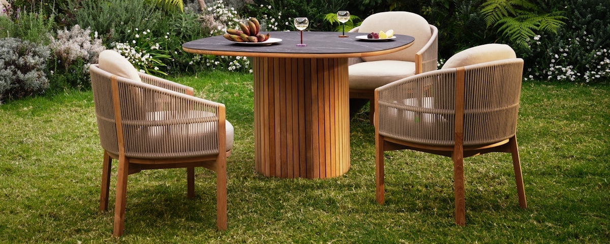 Softlands Outdoor Dining Table surrounded by three Softlands Outdoor Dining Chairs in a lawn setting