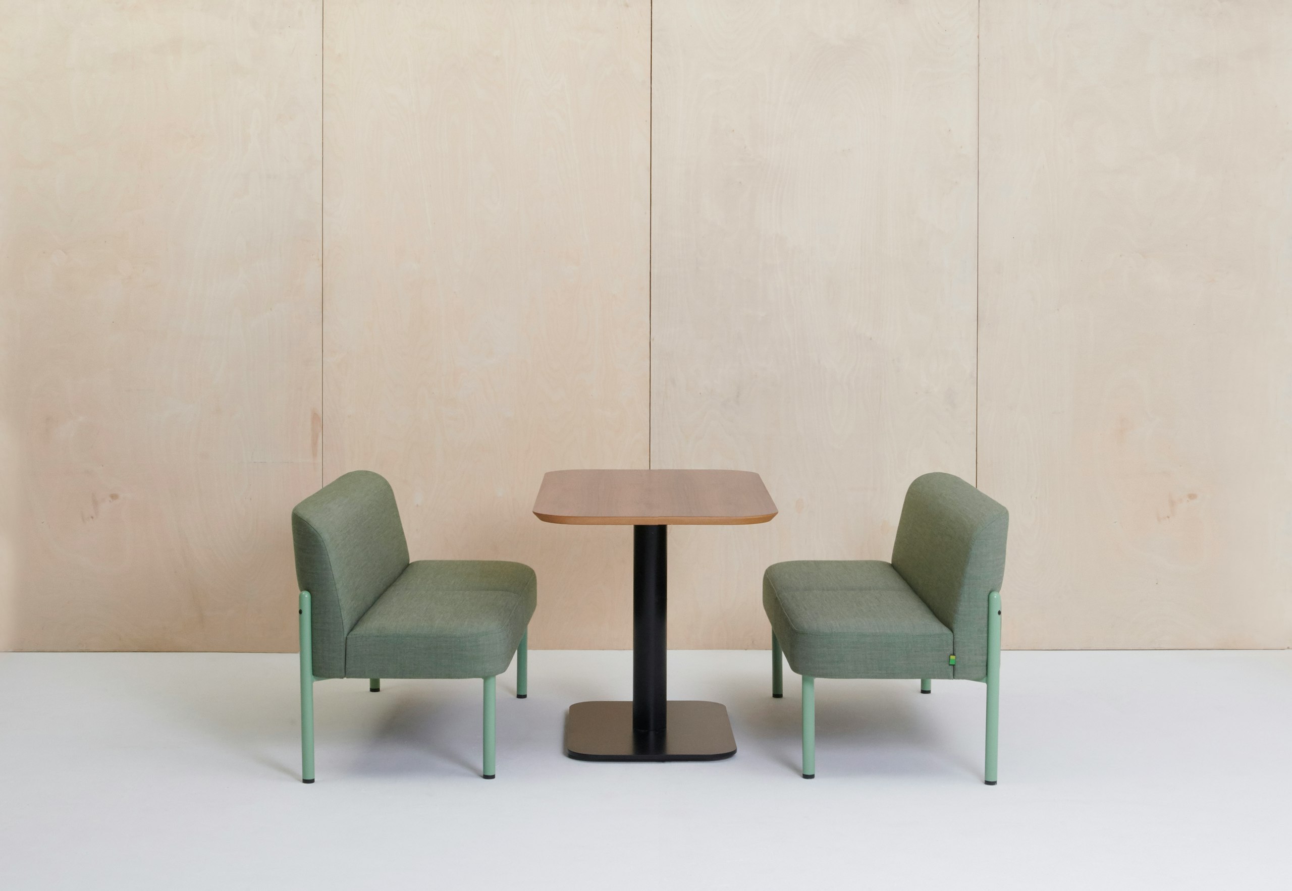 Two Hue sofas in green arranged around a Hue table.