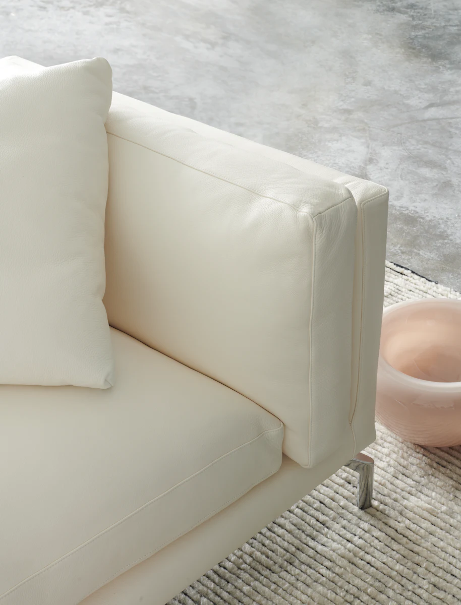 White leather sofa armrest and cushions on a light-colored floor