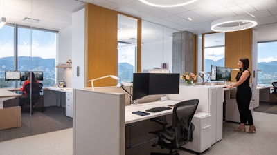 Two people using computers at workstations at Blakes law firm furnished with adjustable height tables and Herman Miller Aeron chairs