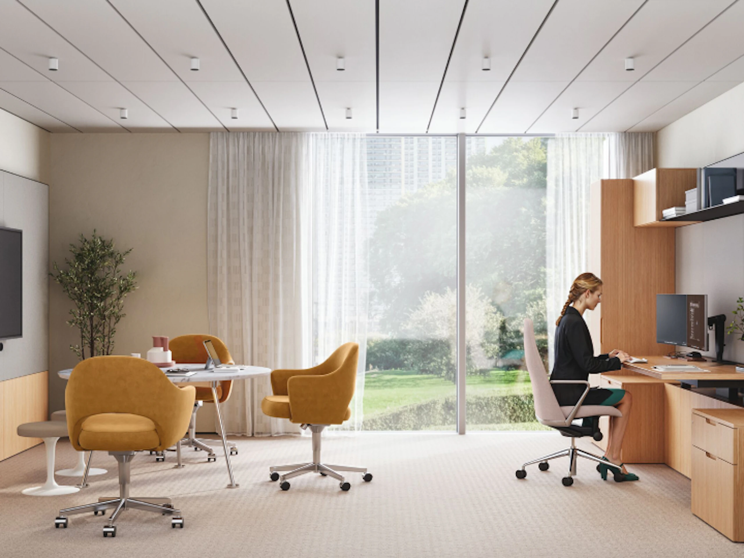 A person working at a computer in a private office setting furnished with Geiger Taper Chairs, a Knoll Grasshopper Table, Saarinen Executive Chairs and Saarinen Tulip Stools.