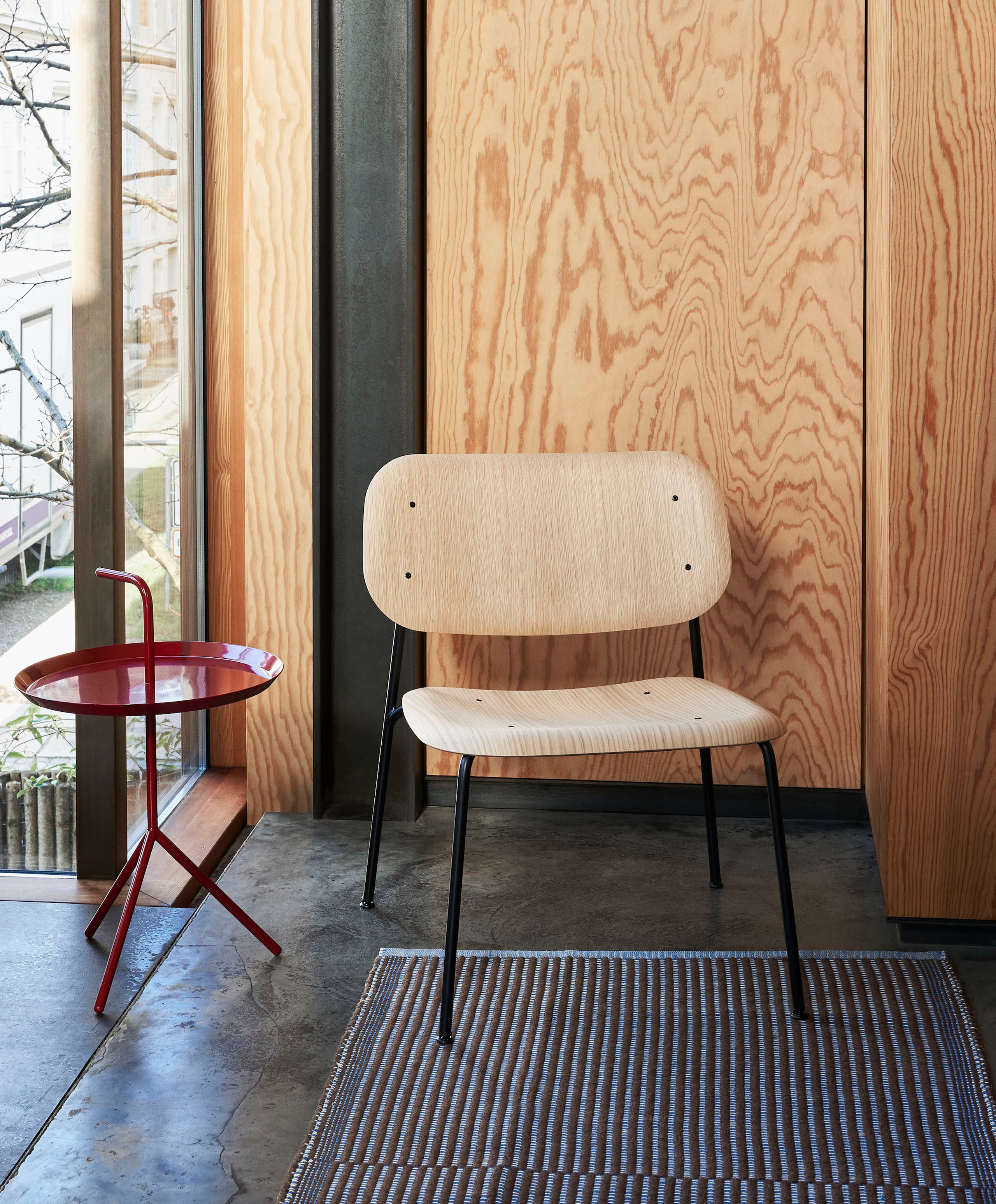 An oak Soft Edge Lounge Chair with a red Don't Leave Me Side Table.