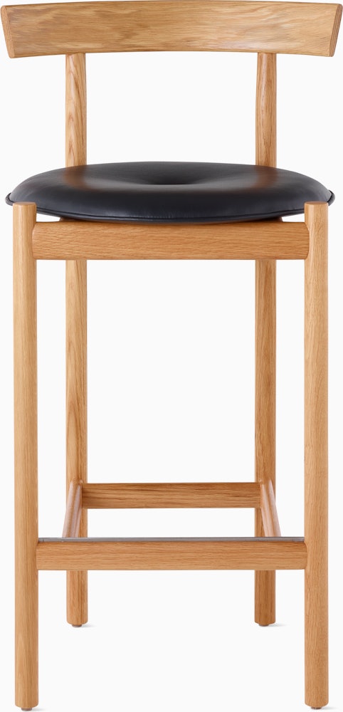 An oak Comma Stool with a seat pad, viewed from the front.
