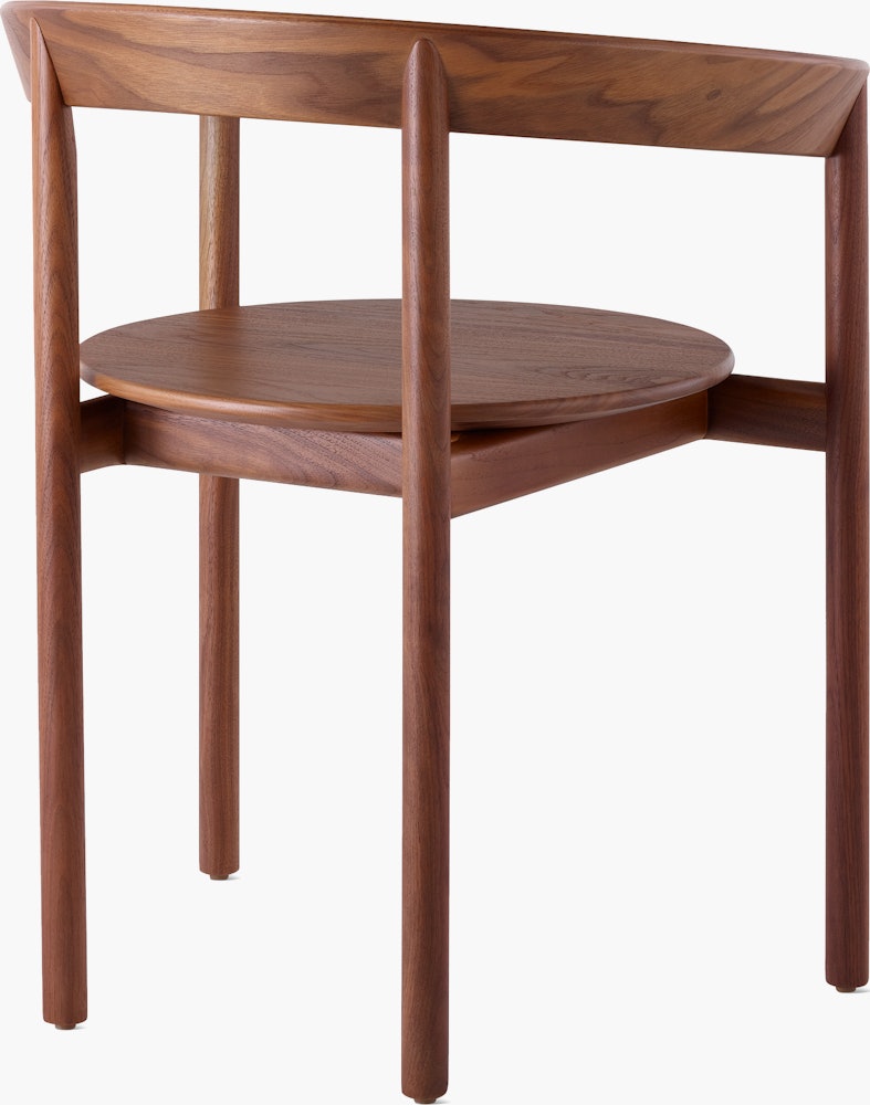 A walnut Comma Chair with arms, viewed from the back at an angle.