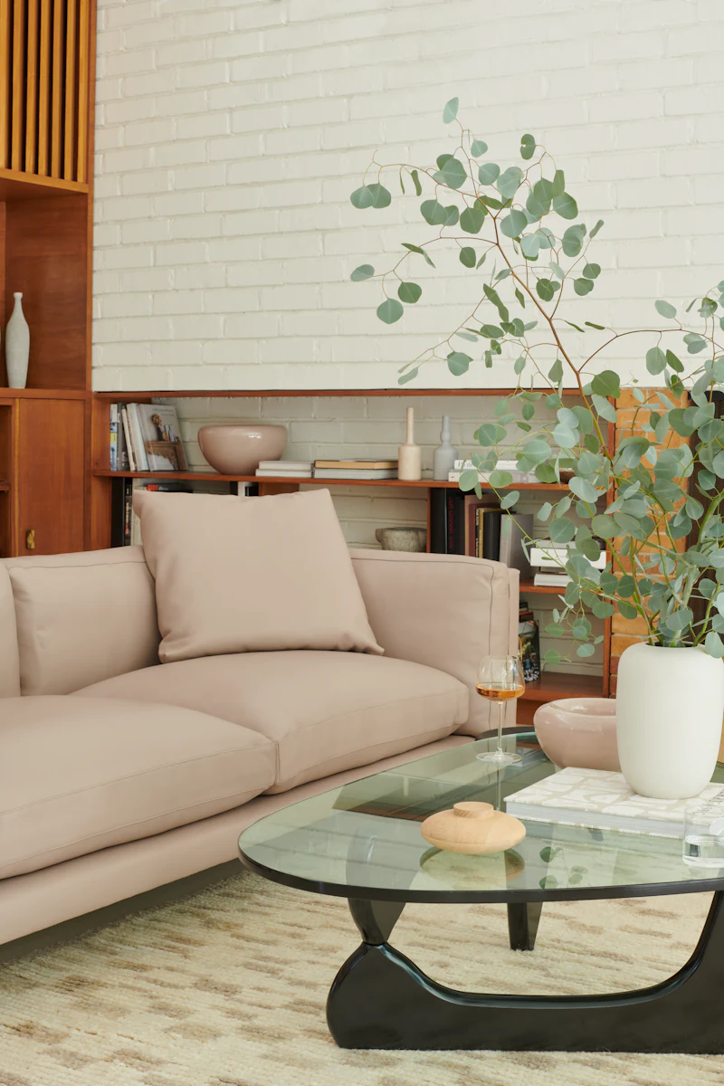 Beige sofa in a cozy living room with wooden shelves and plants