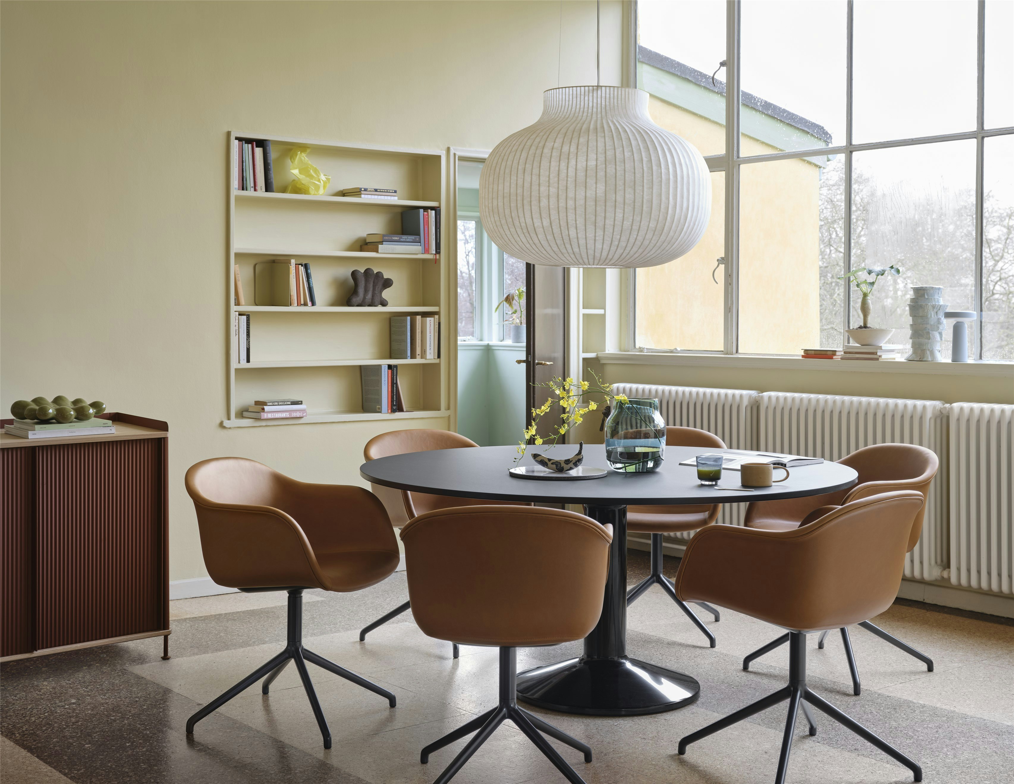 Midst Table Ø160 cm in Black - Fiber Armchair Swivel Base in Refine Leather Cognac/Black - Strand Pendant Lamp Ø60 cm in White - Silent Vase Ø20 cm in Dark Green - Enfold Sideboard 100x45 H85 cm in Deep Red - Ease Portable Lamp in Light Blue
