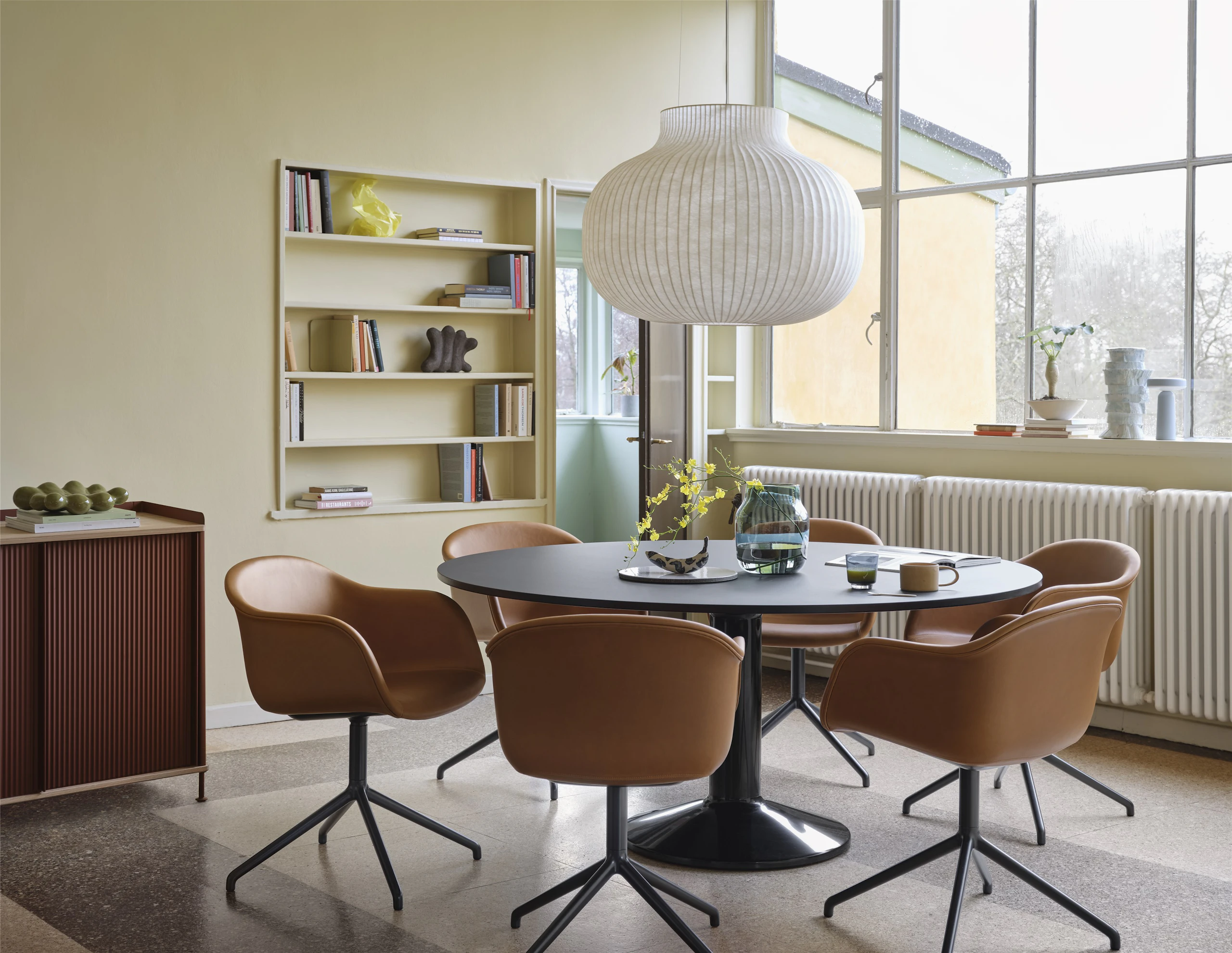 Midst Table Ø160 cm in Black - Fiber Armchair Swivel Base in Refine Leather Cognac/Black - Strand Pendant Lamp Ø60 cm in White - Silent Vase Ø20 cm in Dark Green - Enfold Sideboard 100x45 H85 cm in Deep Red - Ease Portable Lamp in Light Blue