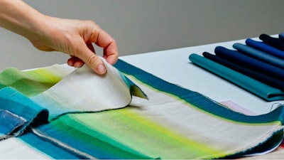 A person holding several pieces of vibrantly colored Maharam textiles