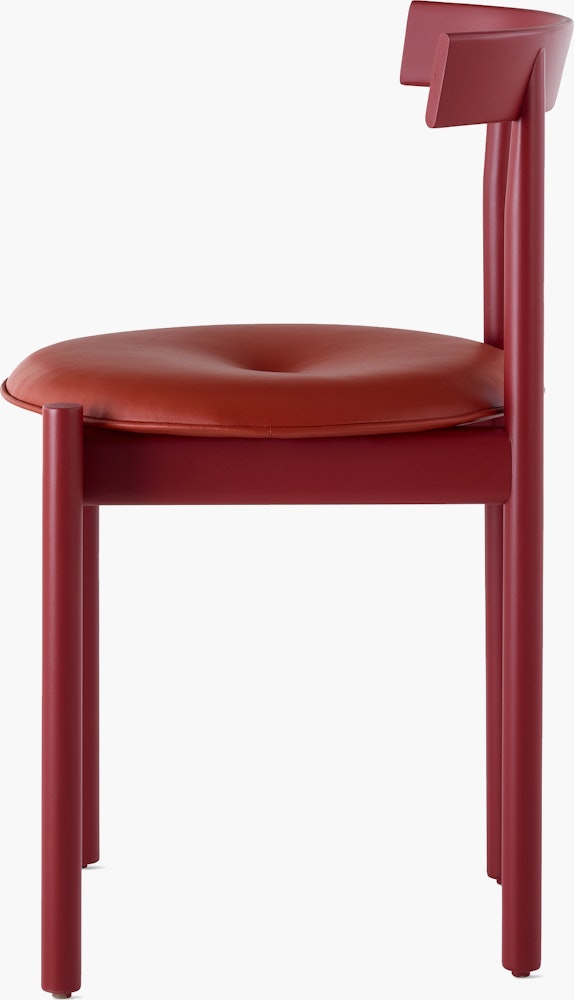 Profile view of a red Comma Chair with a seat pad.