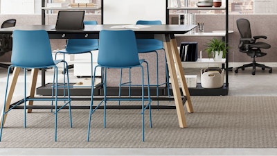A black NaughtOne Morse Bar Table with wooden legs surrounded by four blue bar-height chairs in a team neighborhood setting designed to facilitate change, reduce disruption, and improve resiliency.