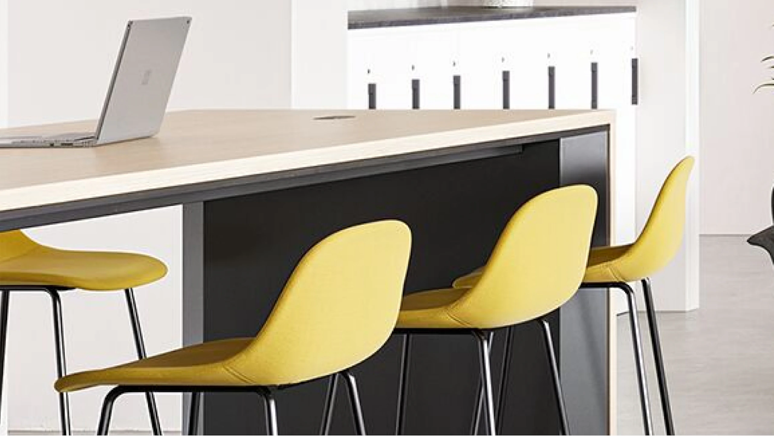 Yellow bar-height stools arranged at a Muuto Base Table used to encourage connection in a community café setting