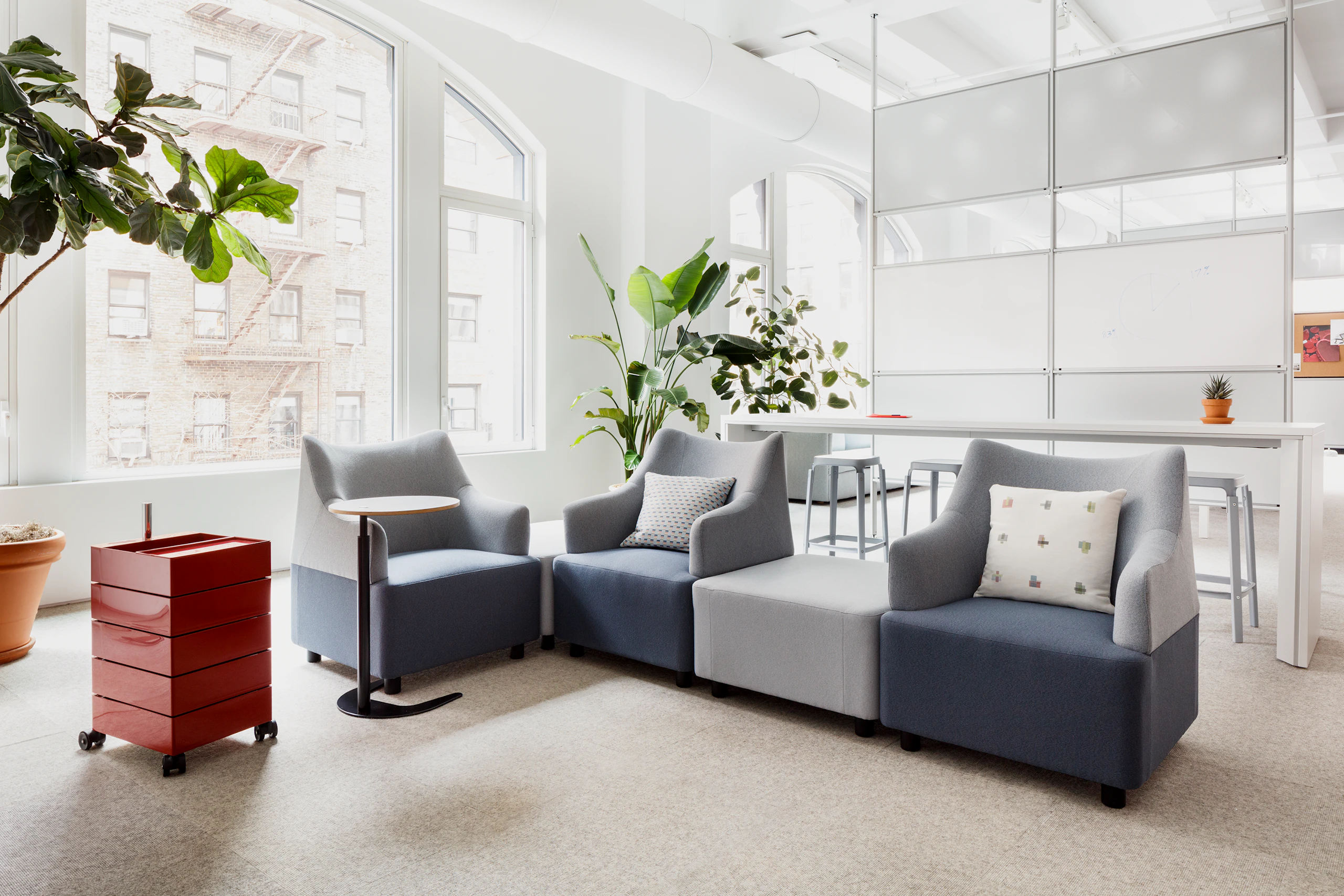 Angled view of two tone blue and gray Plex Modular Seating, with red 360 Containers and black Plex Adjustable Work Table with Maars M923.