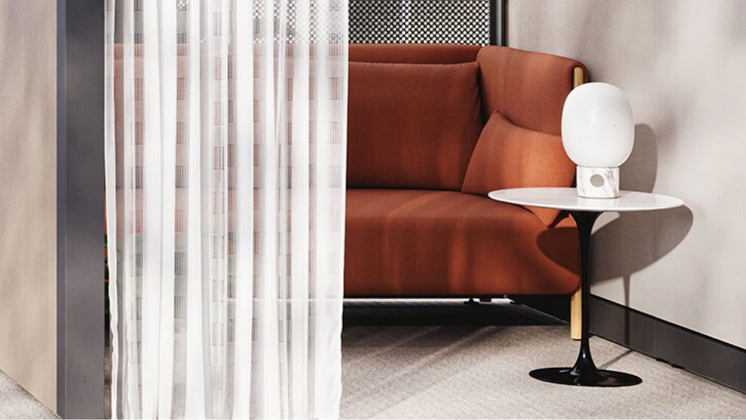 A burnt-orange couch next to a black and white Knoll Saarinen side table in an individual respite space created using Knoll Rockwell Unscripted Creative Walls