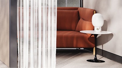 A burnt-orange couch next to a black and white Knoll Saarinen side table in an individual respite space created using Knoll Rockwell Unscripted Creative Walls