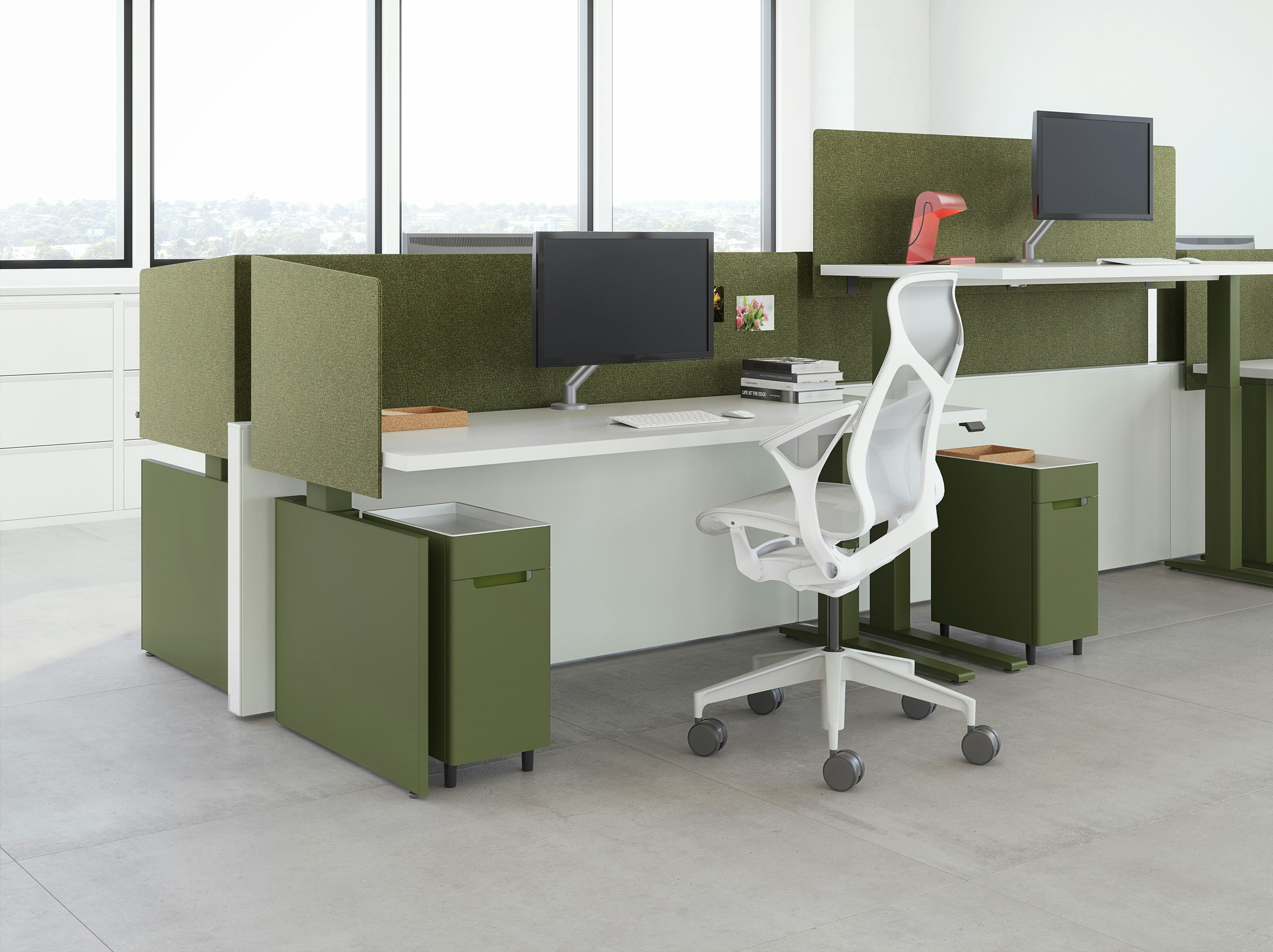 A workspace view featuring height-adjustable table workspaces with Ambit Workspace Solutions in olive color with a grey Cosm chair.