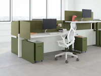 A workspace view featuring height-adjustable table workspaces with Ambit Workspace Solutions in olive color with a grey Cosm chair.
