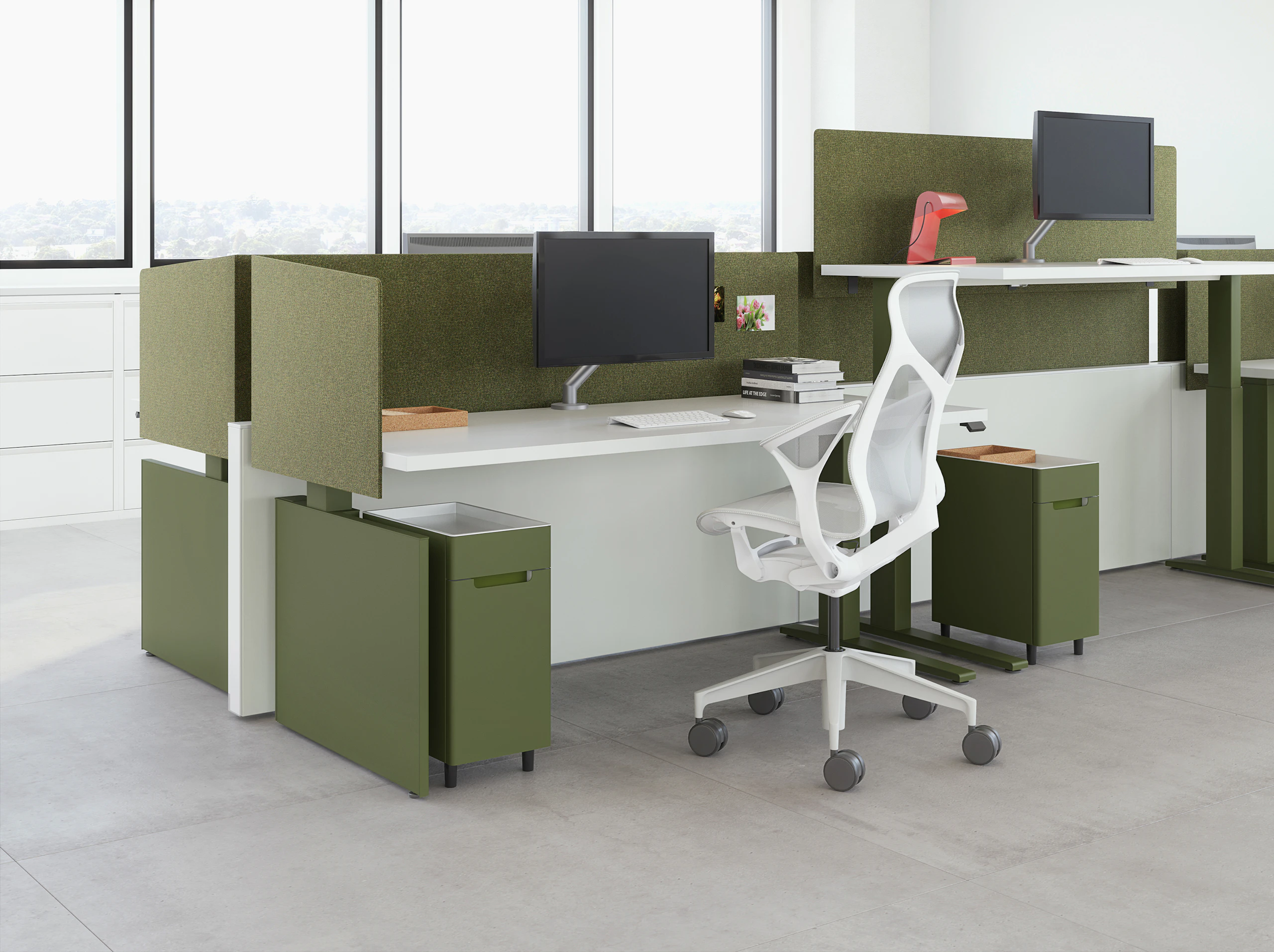 A workspace view featuring height-adjustable table workspaces with Ambit Workspace Solutions in olive color with a grey Cosm chair.